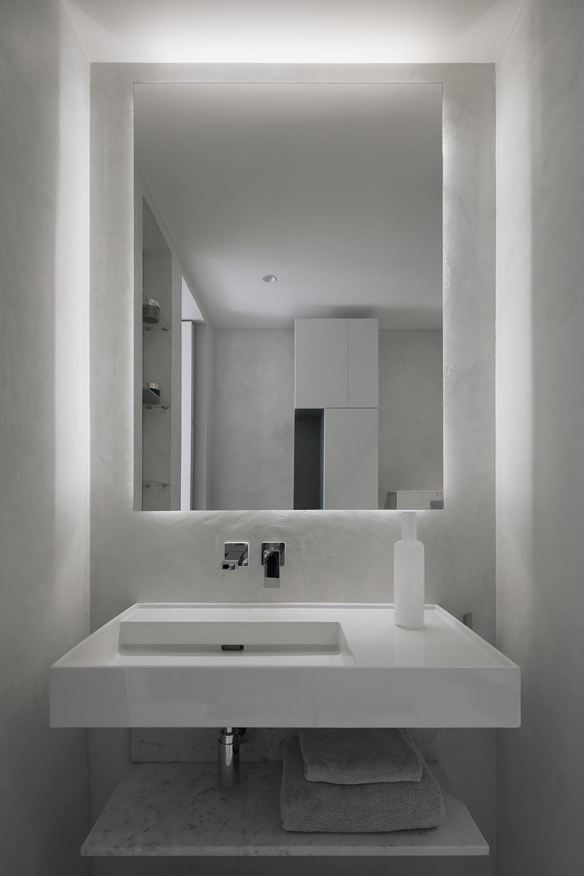 This white master bathroom combines Carrara marble and functional concrete for a contemporary feel.
