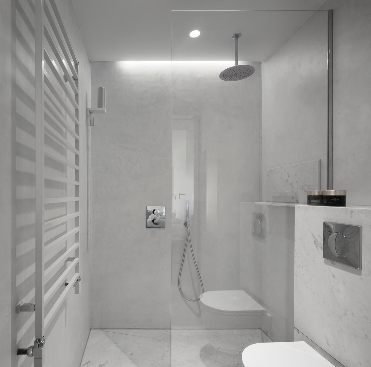 This white master bathroom combines Carrara marble and functional concrete for a contemporary feel.