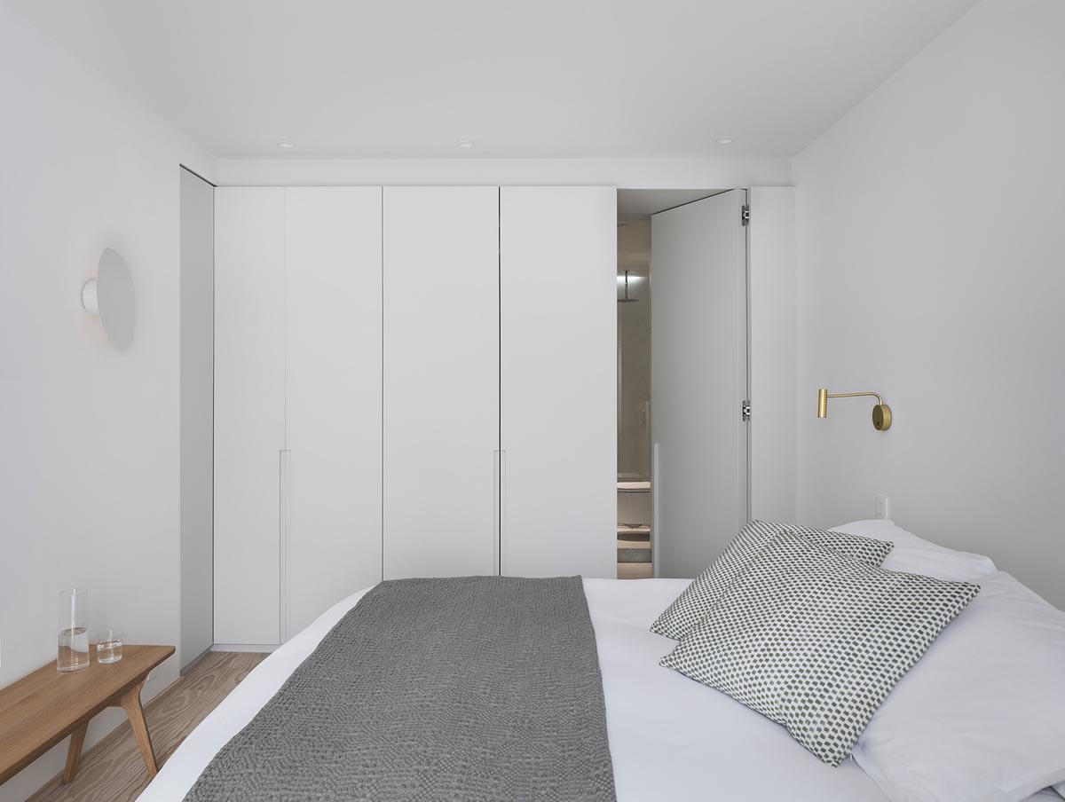 In the master bedroom, bespoke joinery and neutral colors are accented by a gray bed frame and bedding, and a touch of brass.