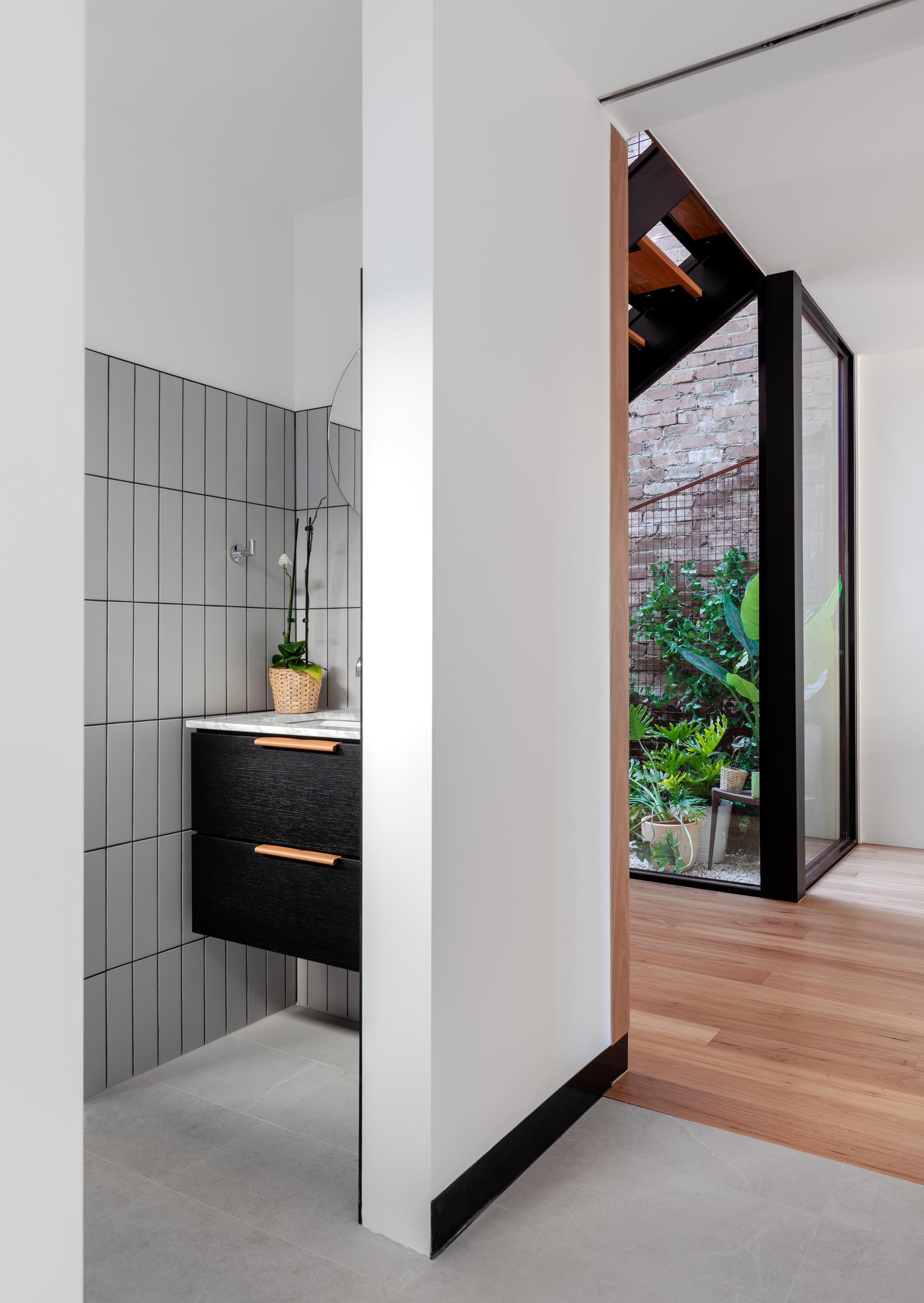 A modern bathroom with light gray rectangular tiles and a black vanity.