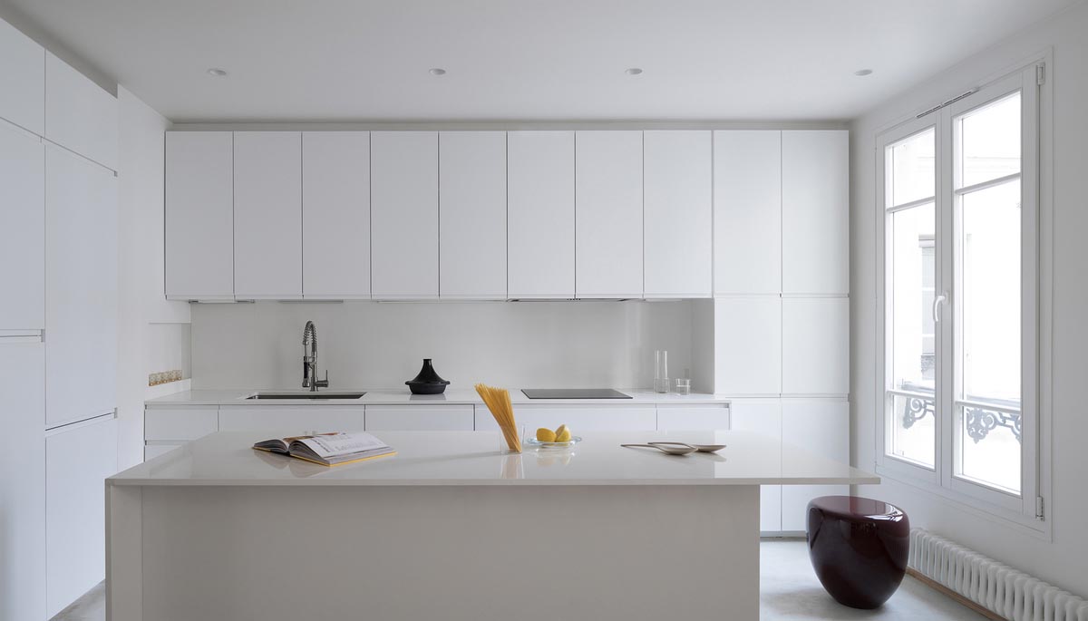 A white kitchen with minimalist cabinets and a large island.