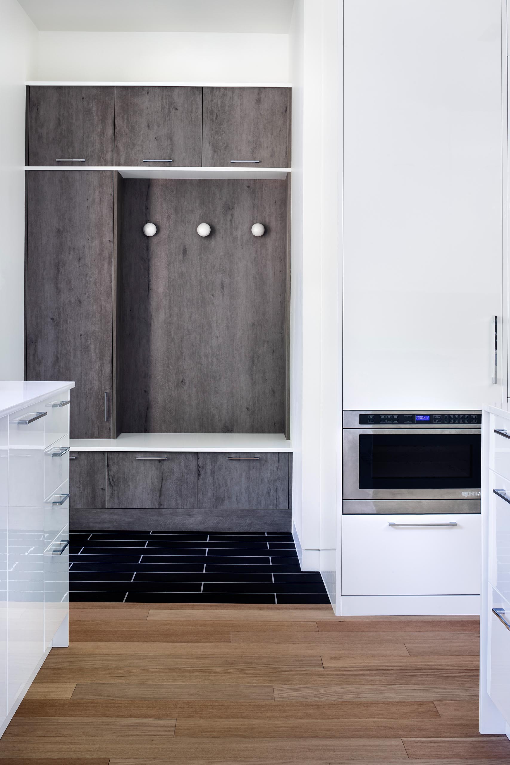 A modern white kitchen with a small mud room.