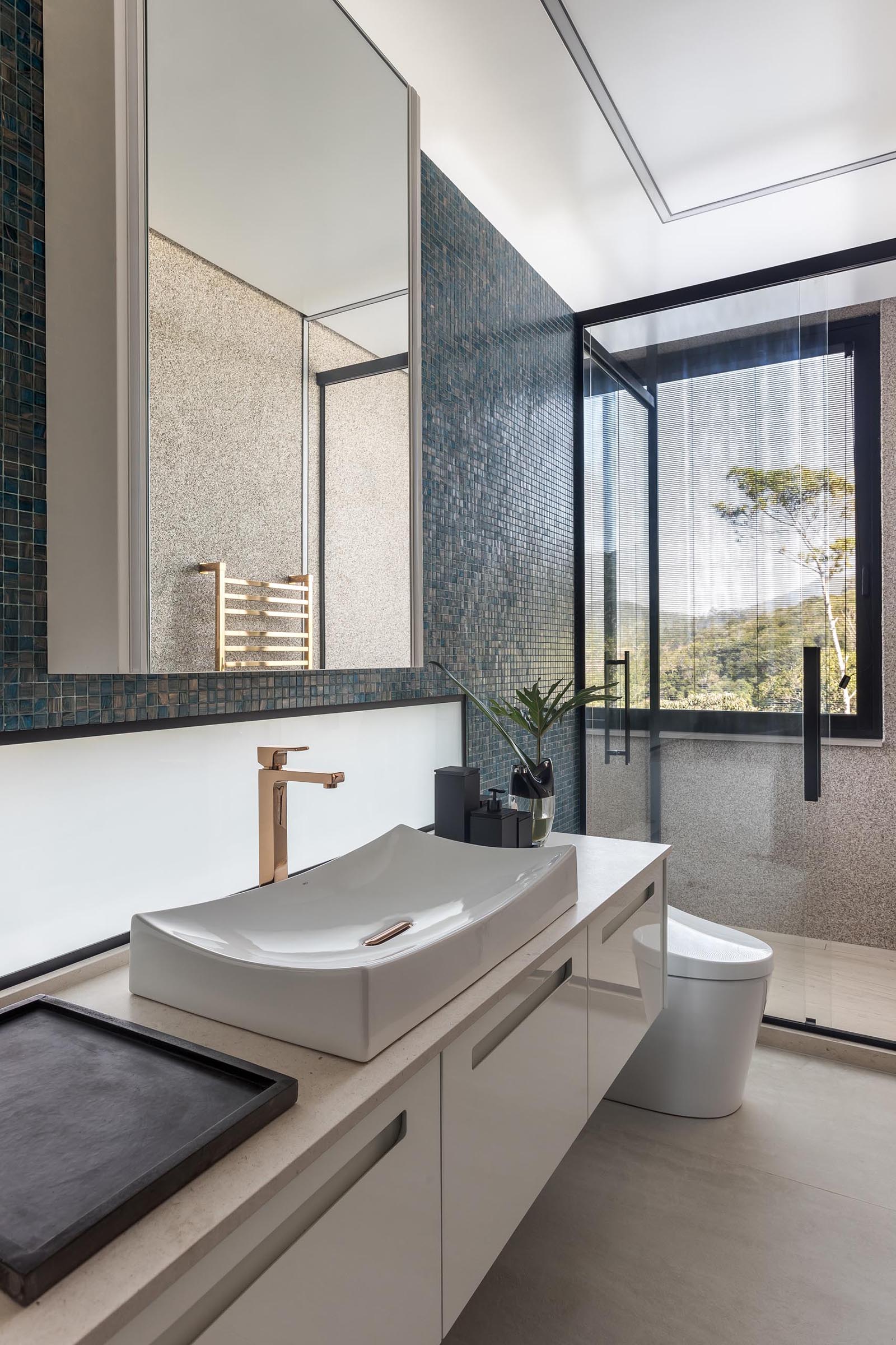 A blue tiled accent wall provides a backdrop for the white vanity and mirror in this modern bathroom.