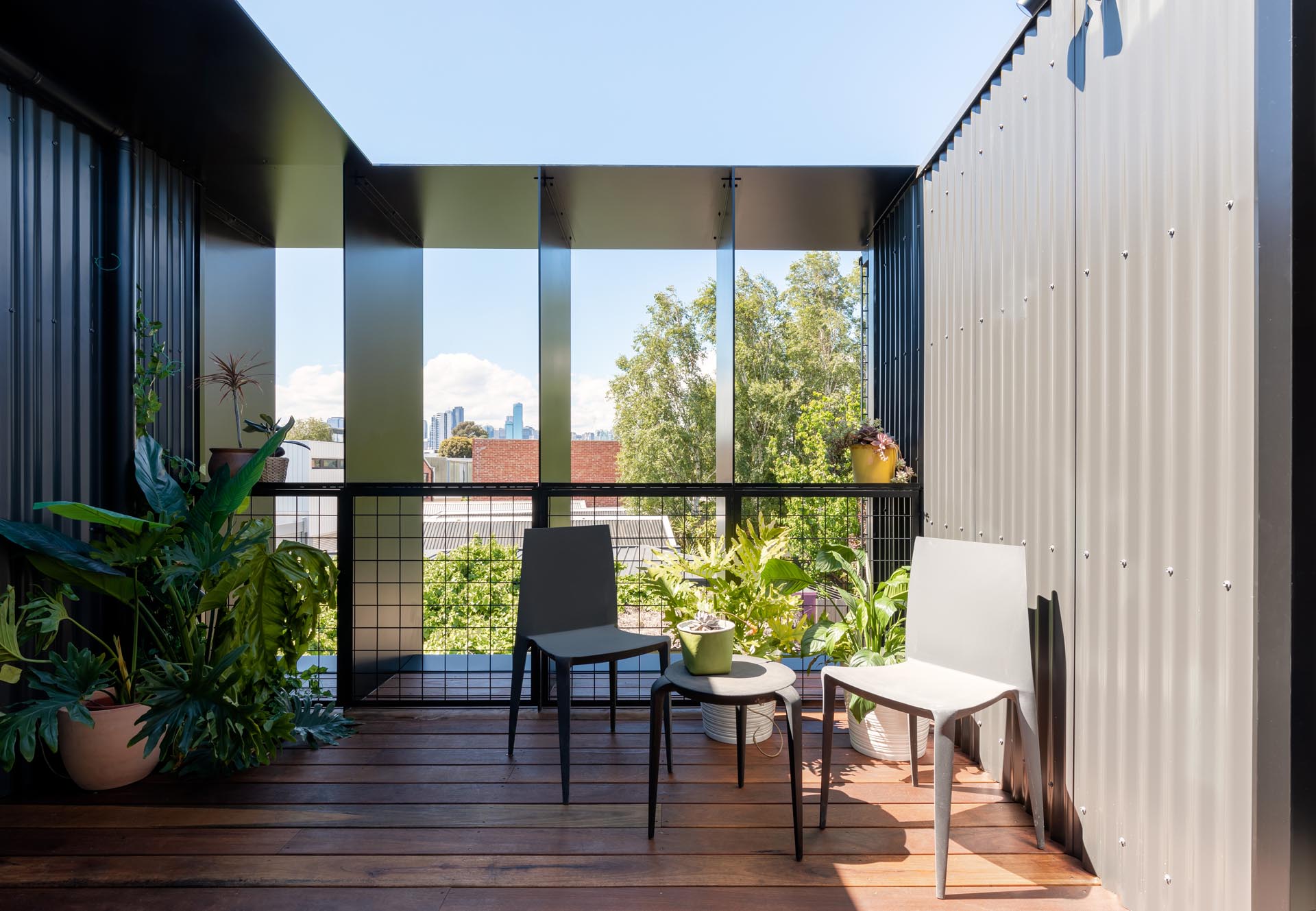 A semi-private deck with wood flooring and corrugated metal siding.