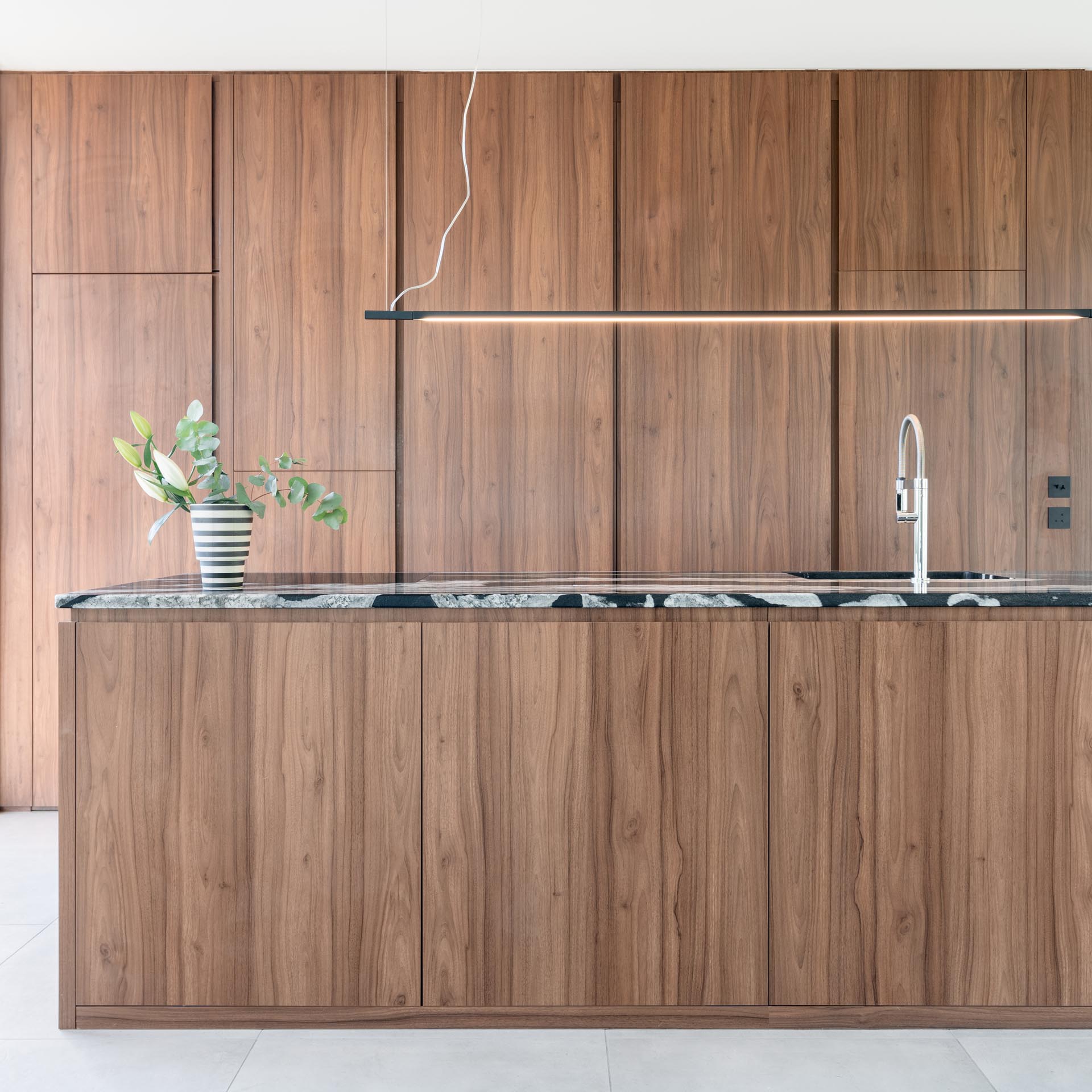 In this modern kitchen, minimalist warm wood cabinets have been used along the wall and the island.