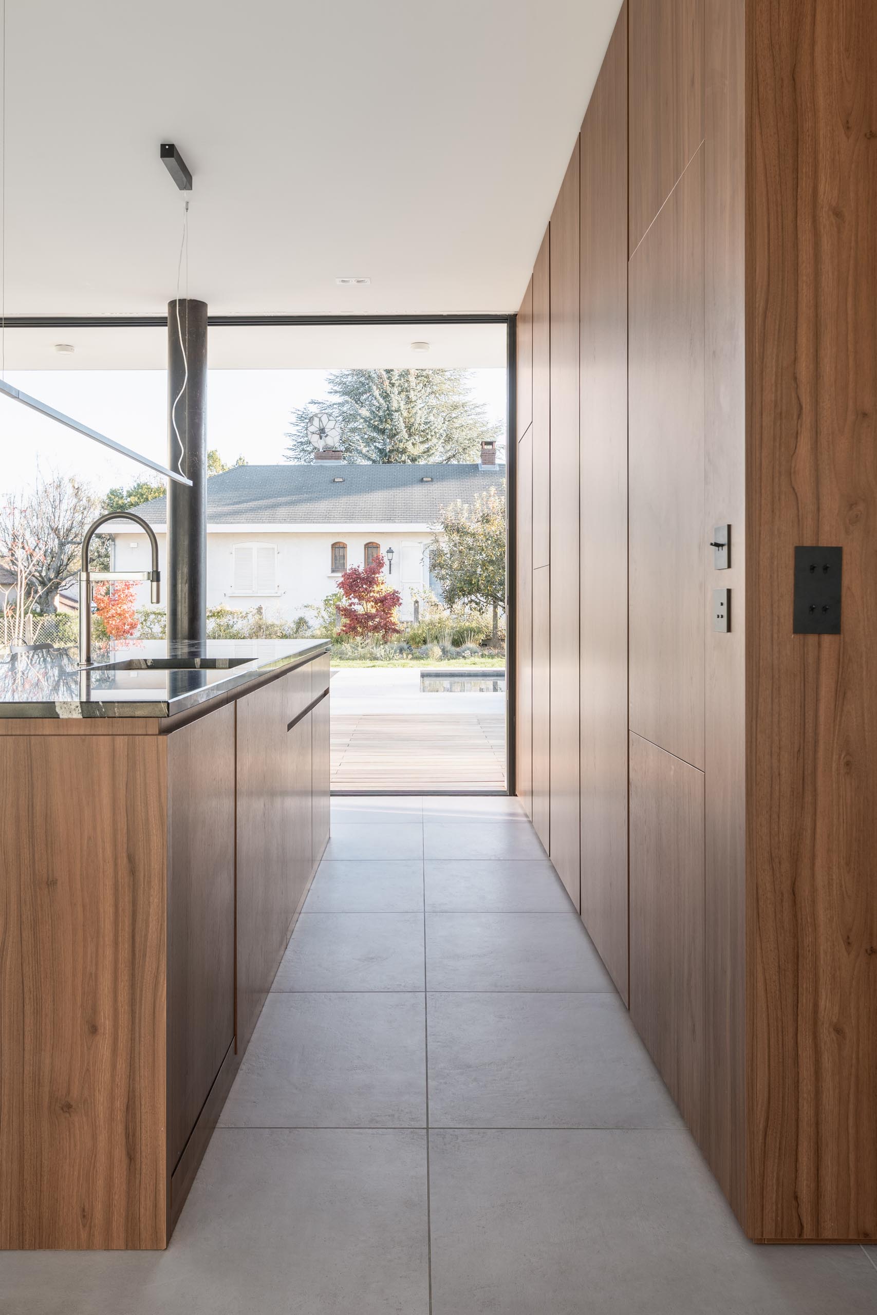 In this modern kitchen, minimalist warm wood cabinets have been used along the wall and the island.