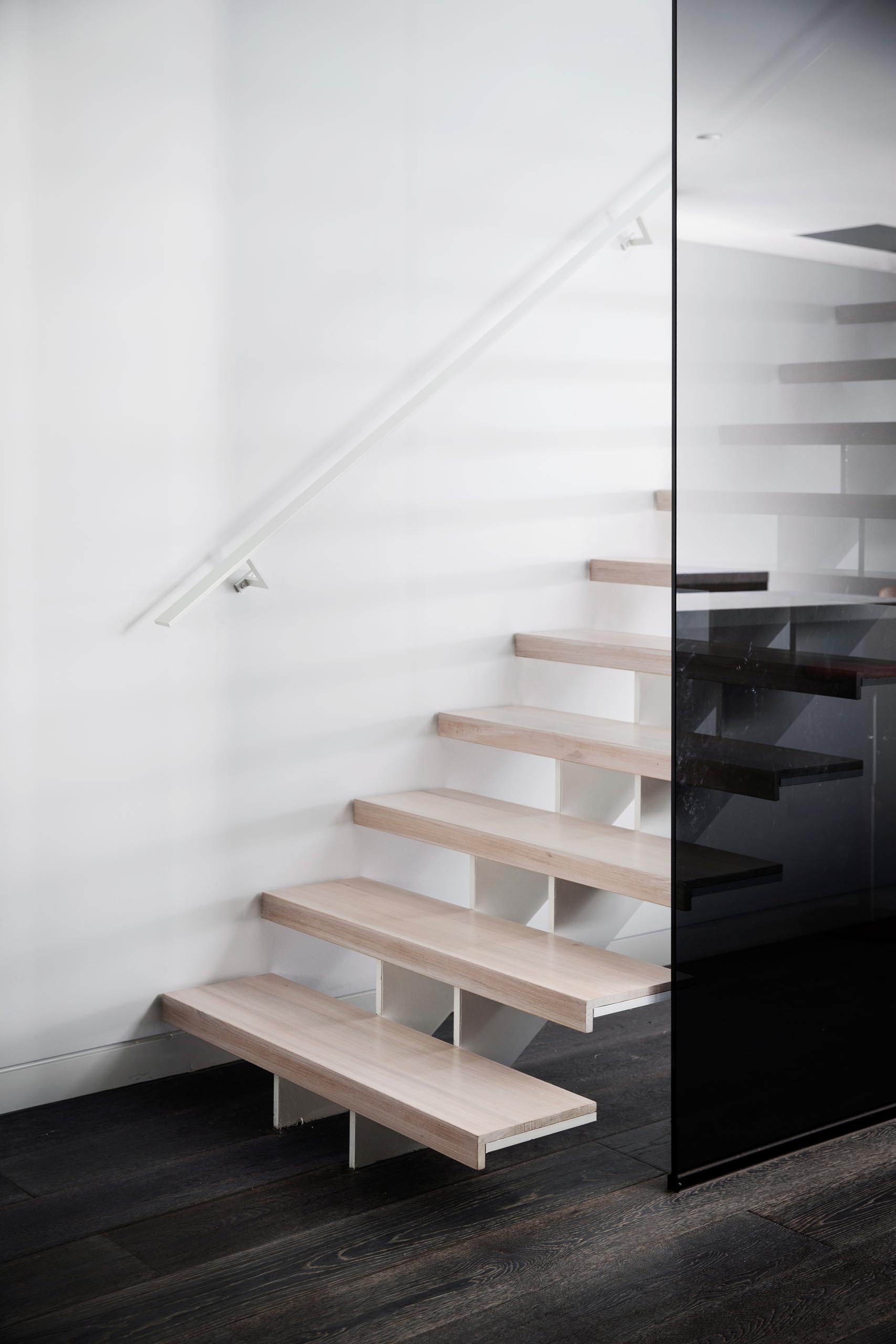 Modern light wood stairs with a white steel support and matching handrail.