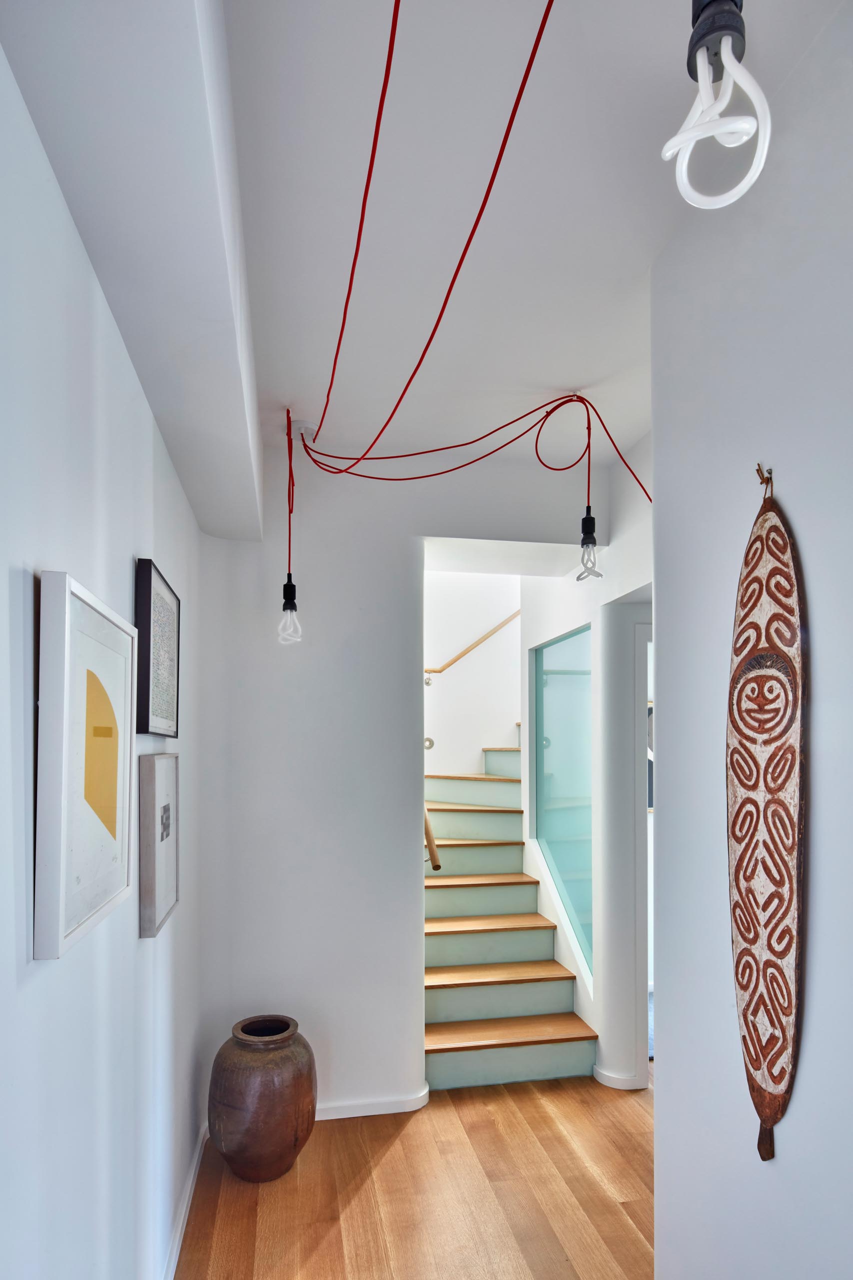 A staircase with wood treads opens up to a hallway with artwork.