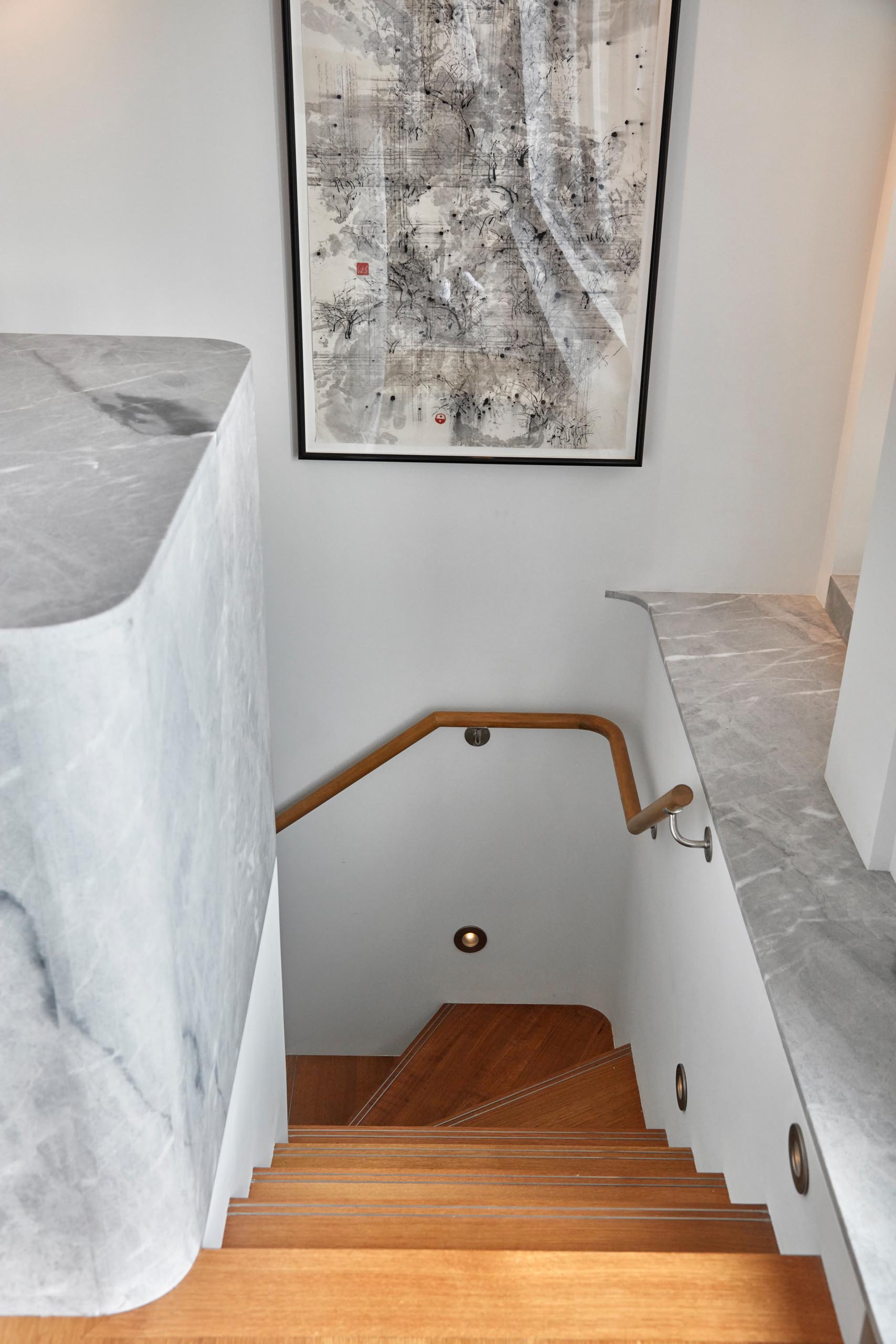 Contemporary stairs with wood treads and small lights built into the white walls.