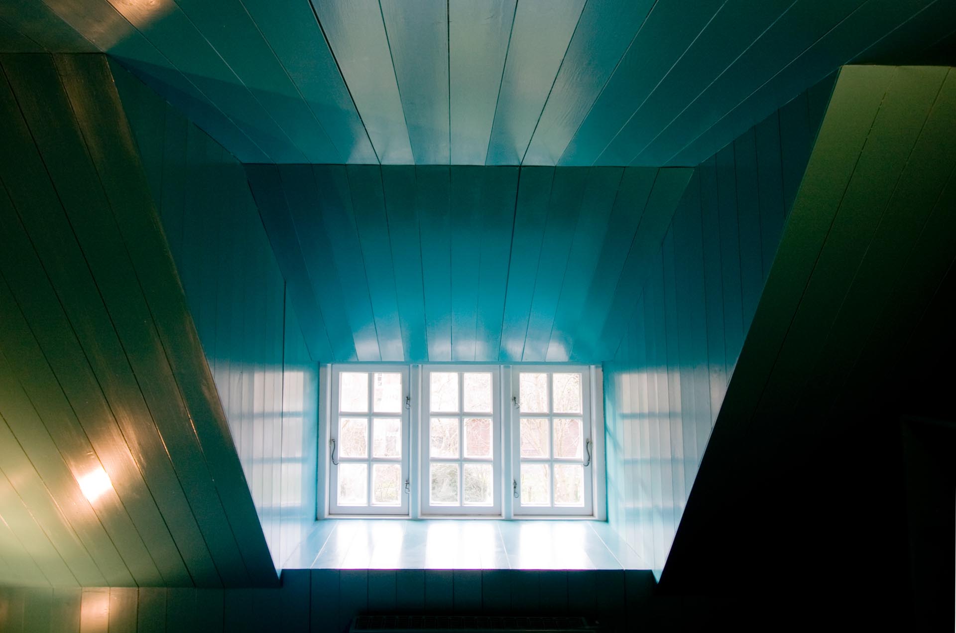 A turquoise blue bedroom with white window frames.