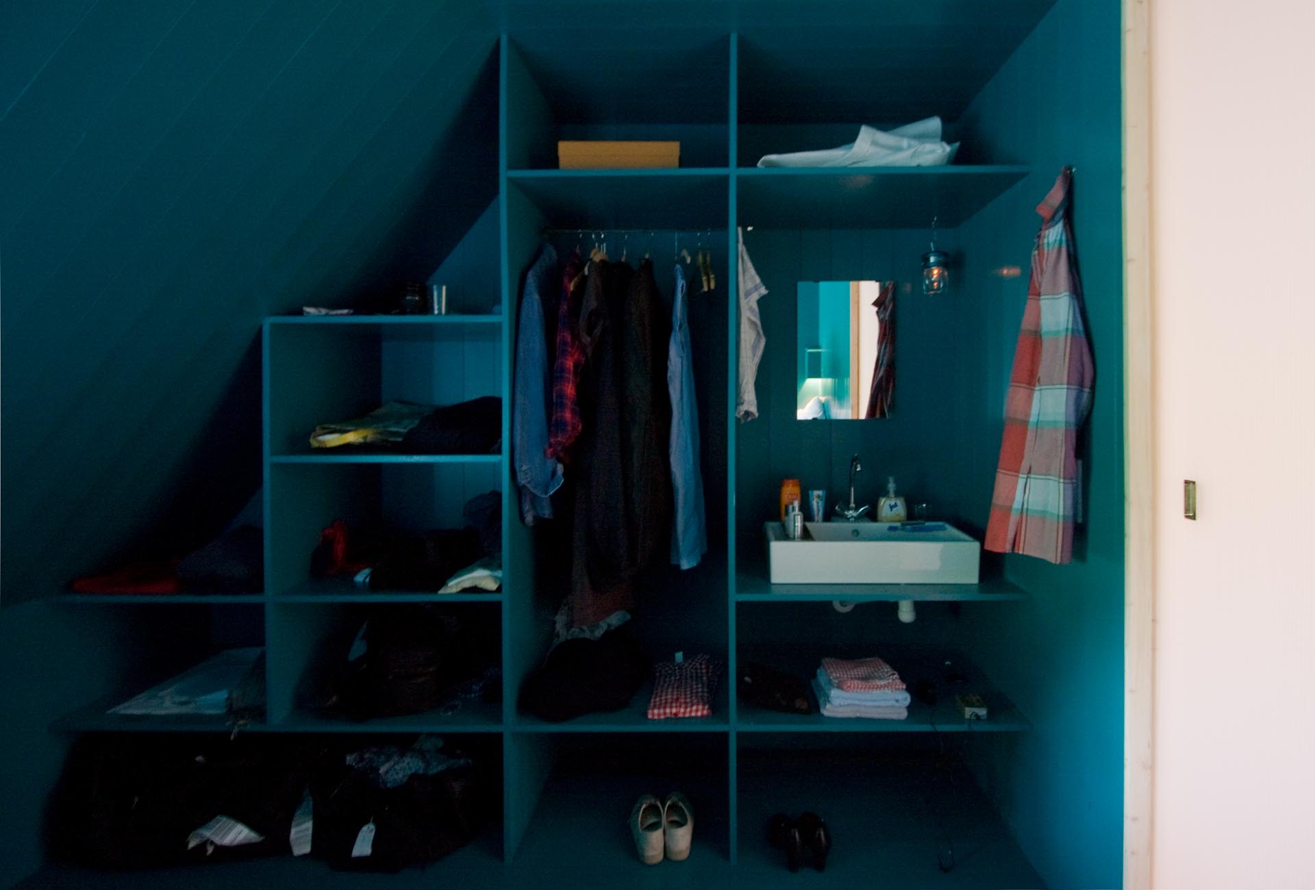 A modern turquoise blue closet that includes a vanity.