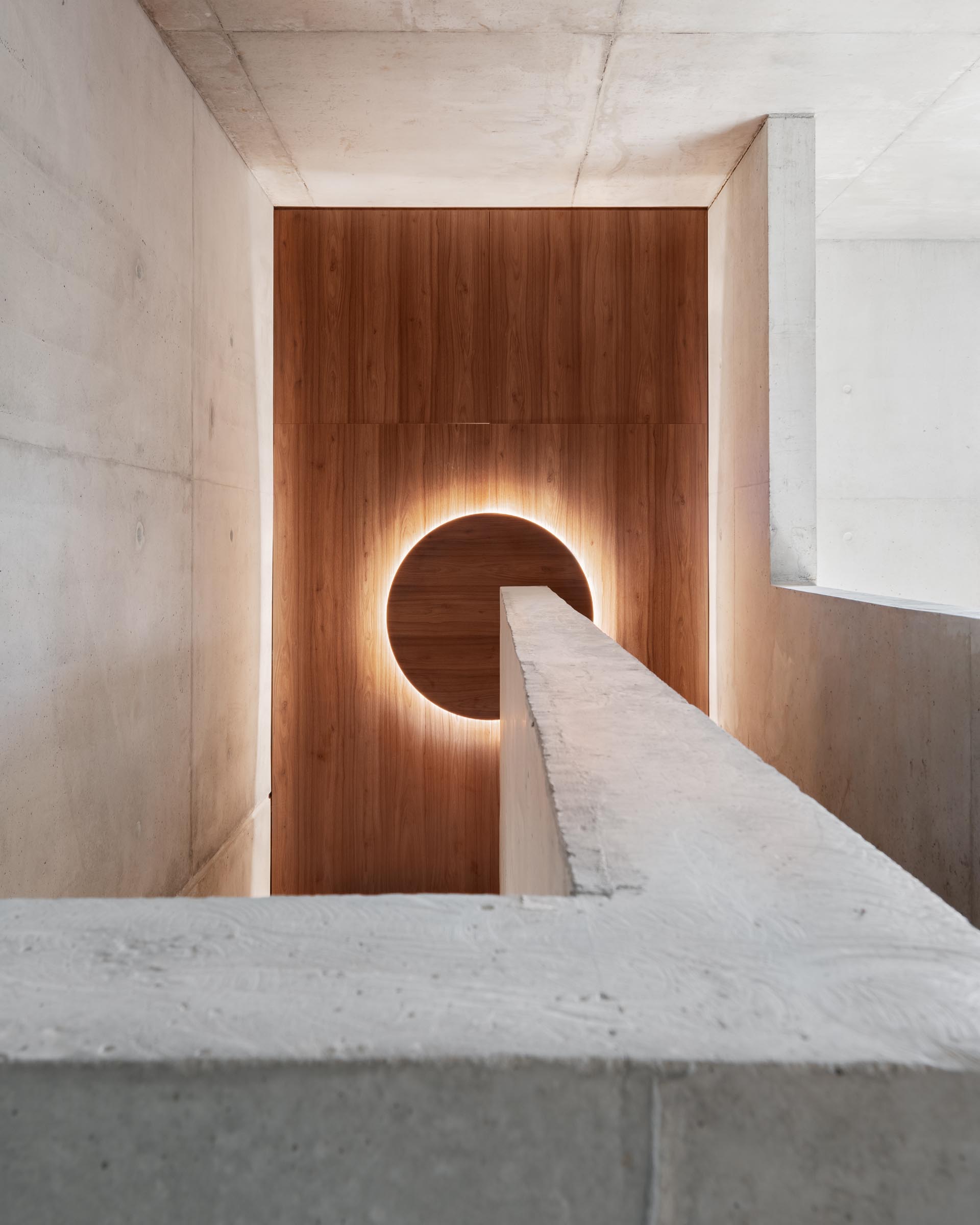 A concrete home with a wood accent wall and round light.