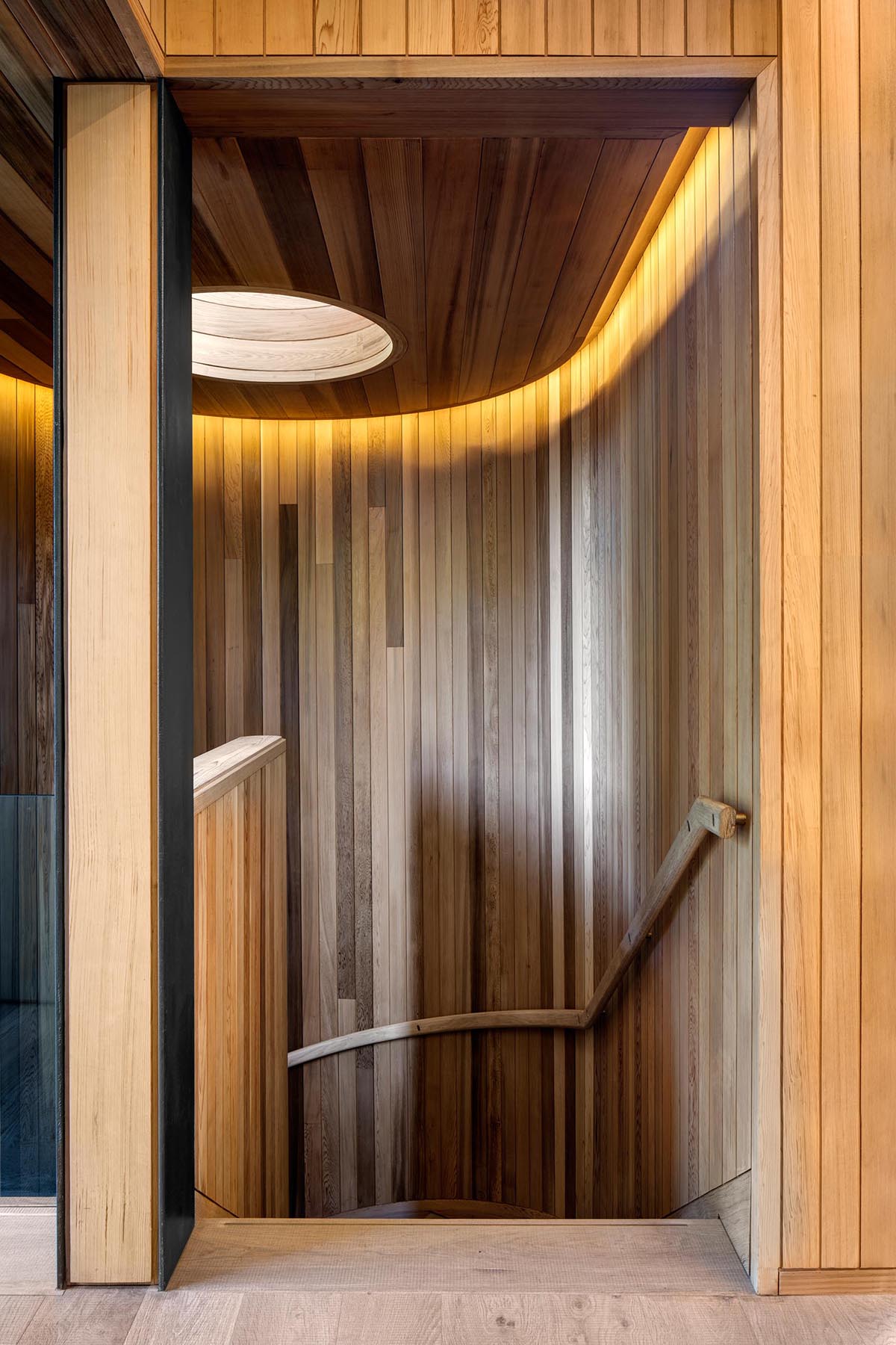 Cầu thang lót gỗ hiện đại với giếng trời và ánh sáng ẩn.