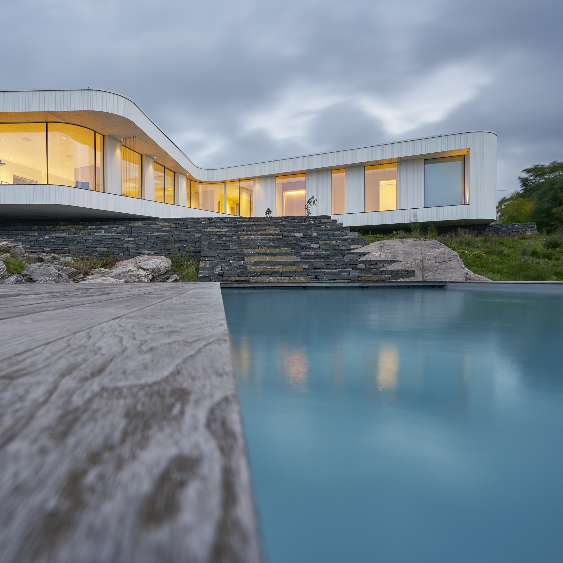 A modern white villa with stone steps and a swimming pool.