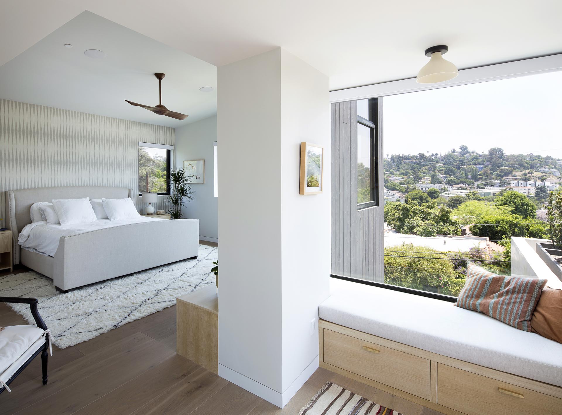 A modern master bedroom with a window seat that has drawers underneath it, keeping stored items hidden from view.