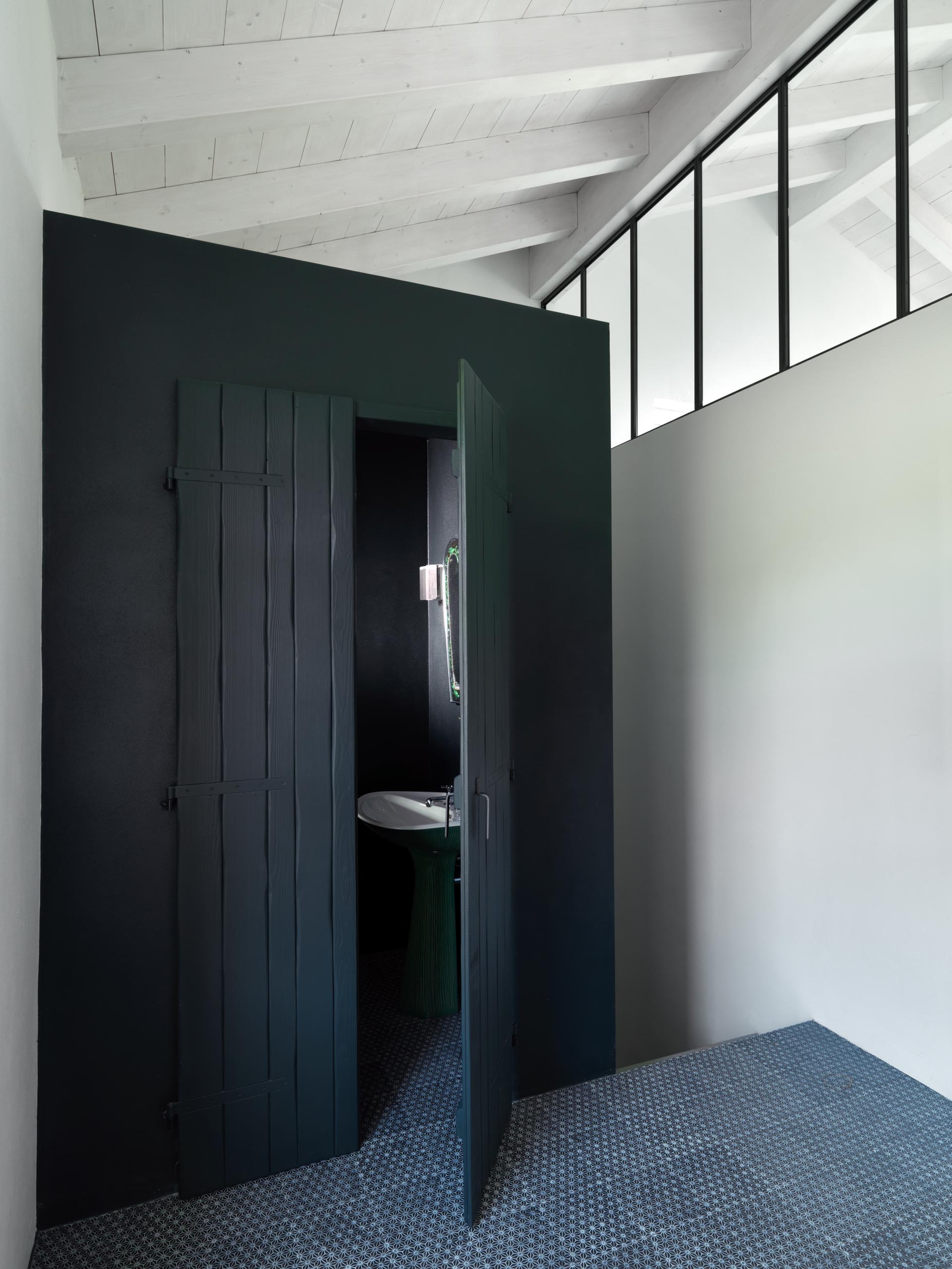 A powder room with matte black painted wood doors.