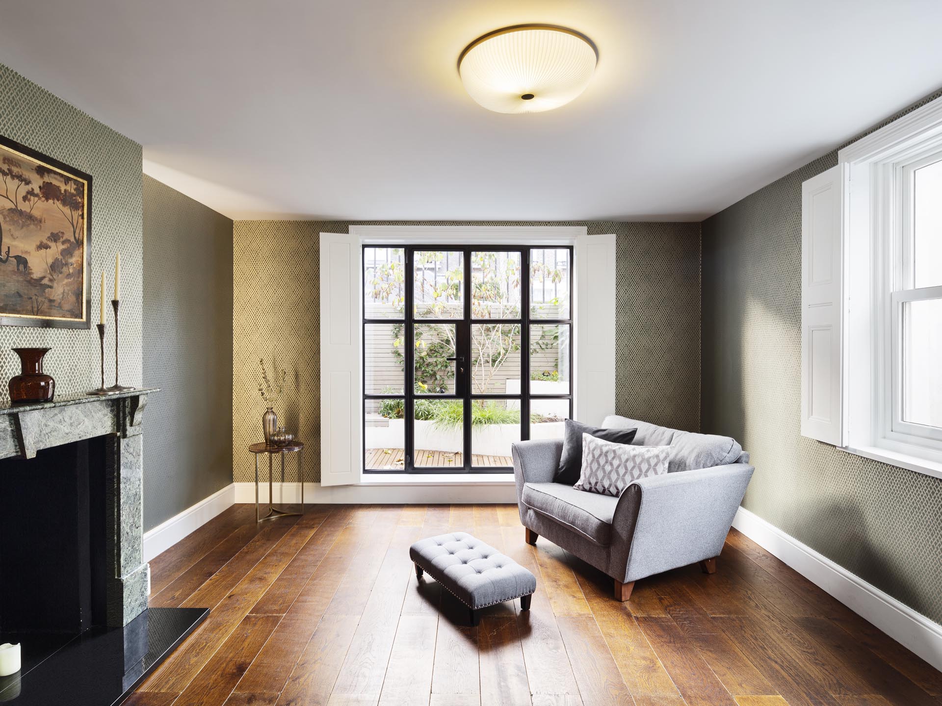 A sitting room with wood floors and black-framed doors.