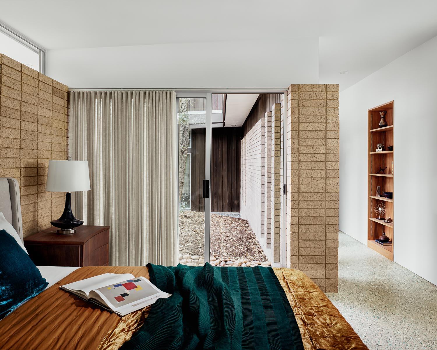 A sliding glass door in this mid-century modern inspired bedroom connects the space with the outdoors.