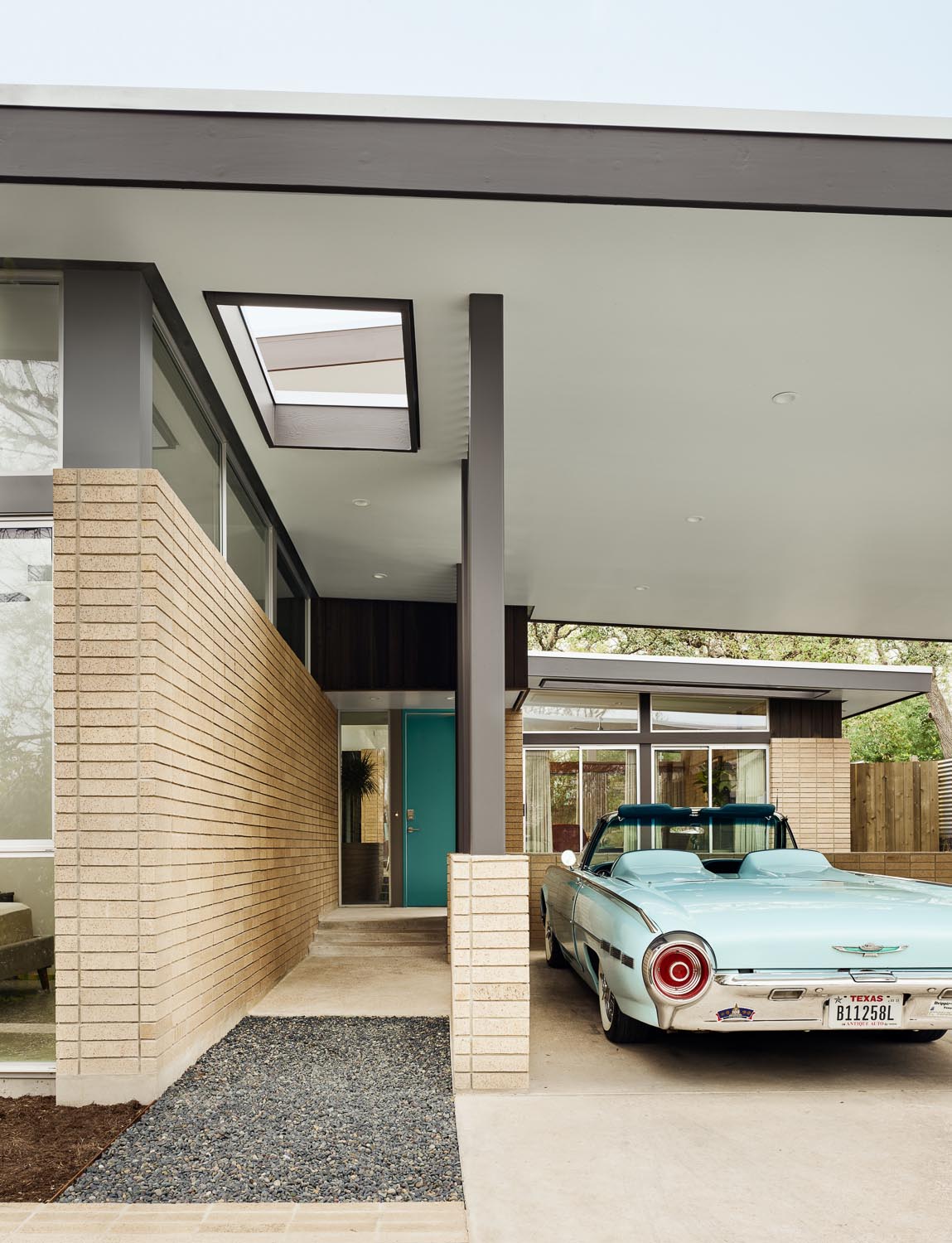 A mid-century modern inspired home with a turquoise front door and a carport.