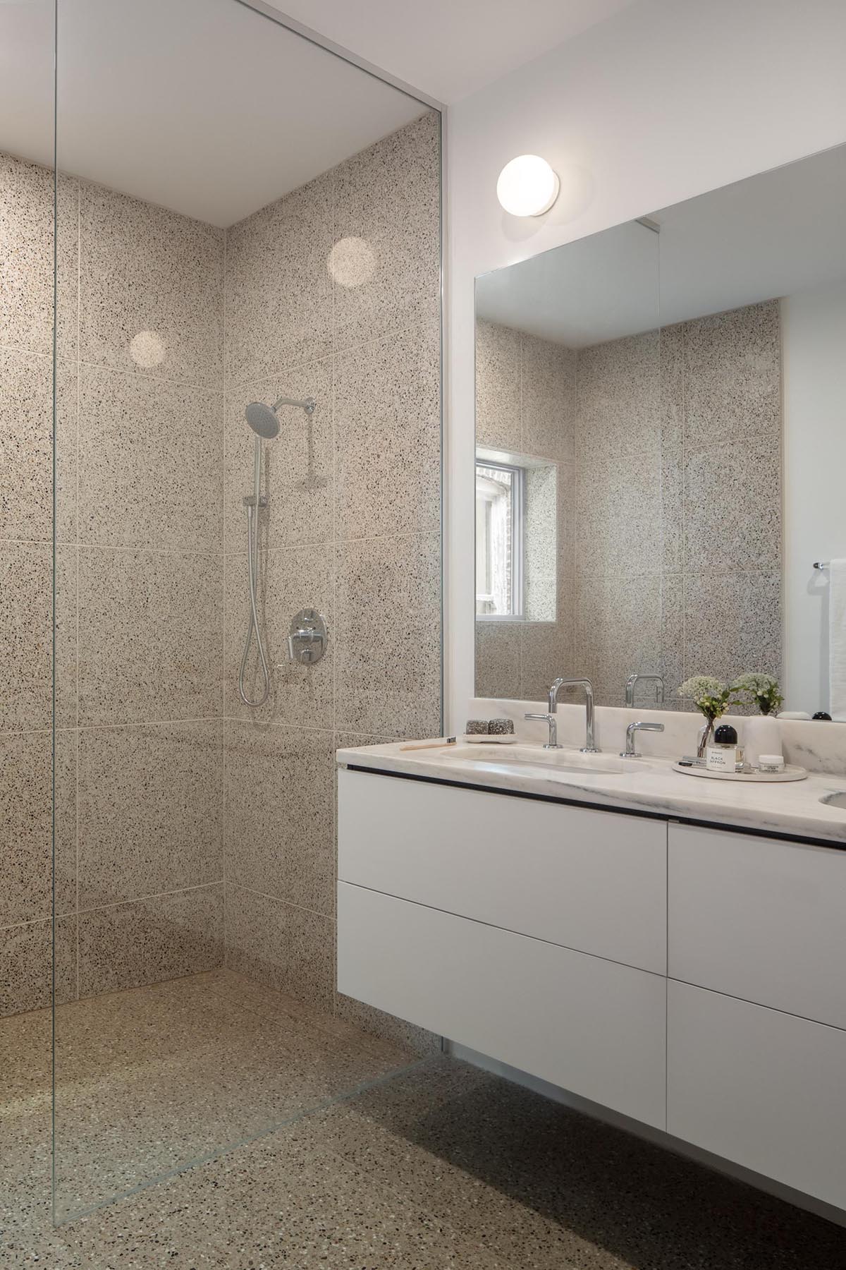 This modern bathroom features large format tiles and a white vanity.