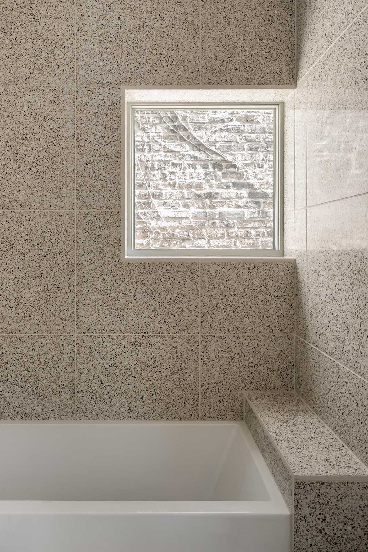 This modern bathroom features large format tiles and a built-in bathtub.