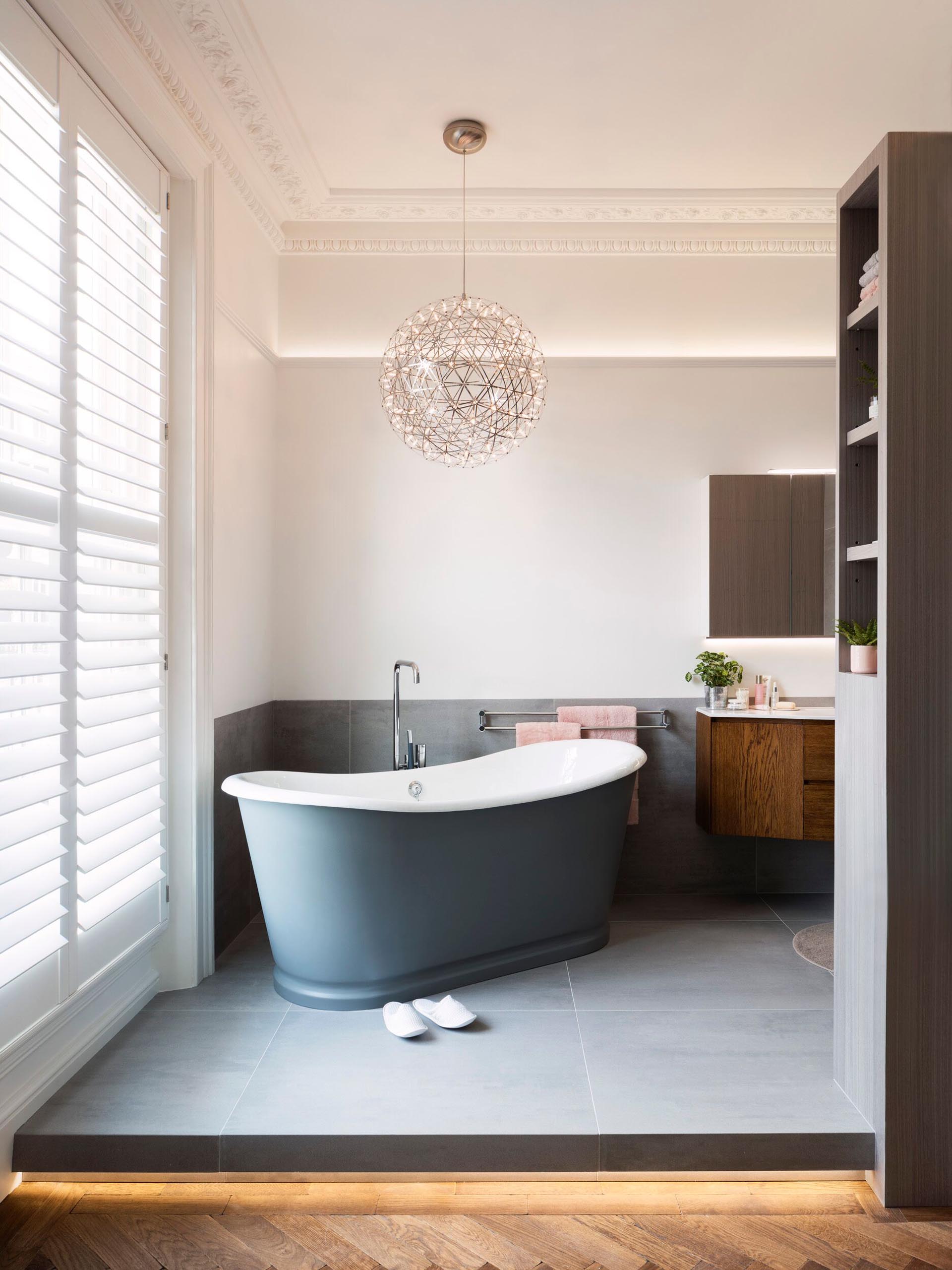 In this master bathroom, the floor has been raised is home to a freestanding bathtub and a shower with a black framed door.