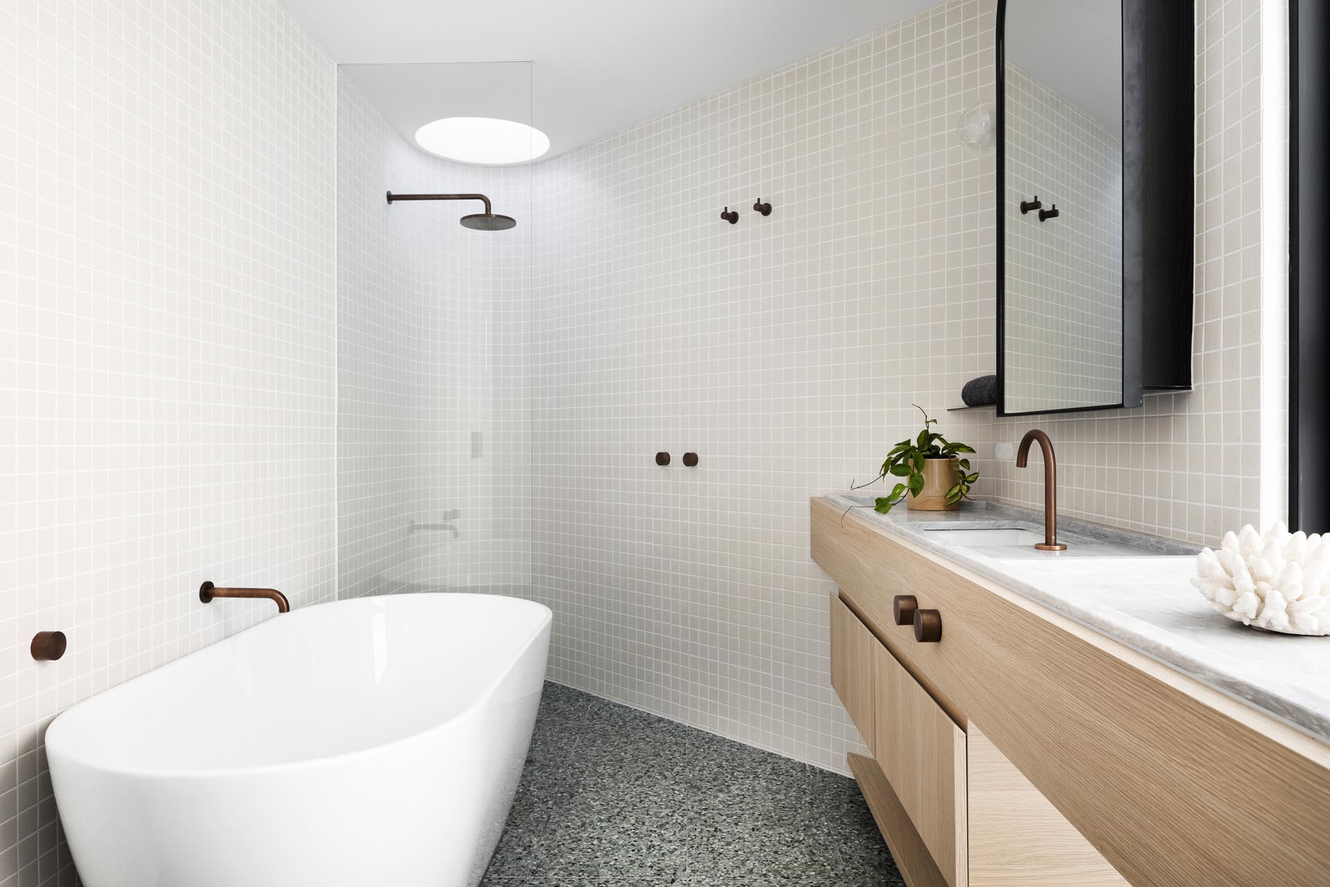 A modern bathroom with a wood vanity and curved shower wall.