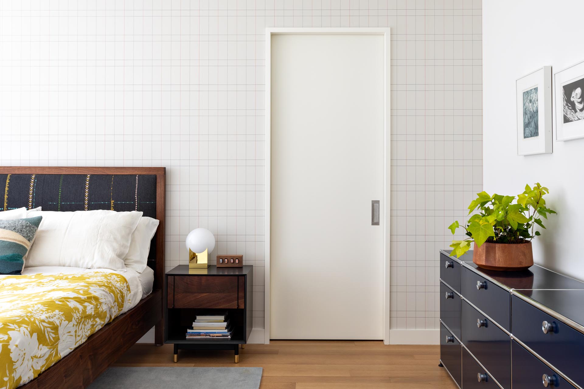 A modern master bedroom that includes wood furniture, pops of color, and a graphic accent wall.