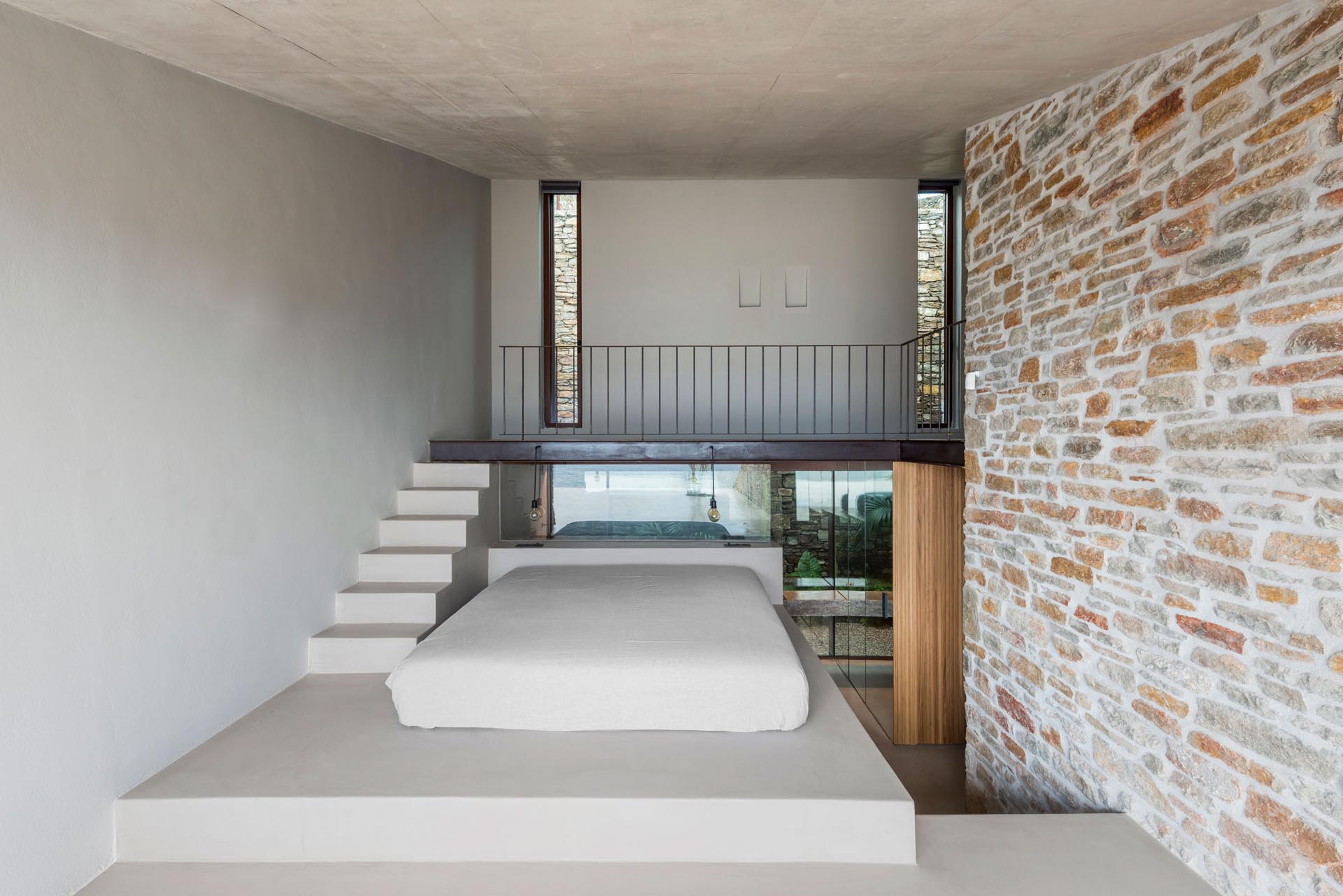 A minimalist bedroom with a bed raised on a platform to take advantage of water views.