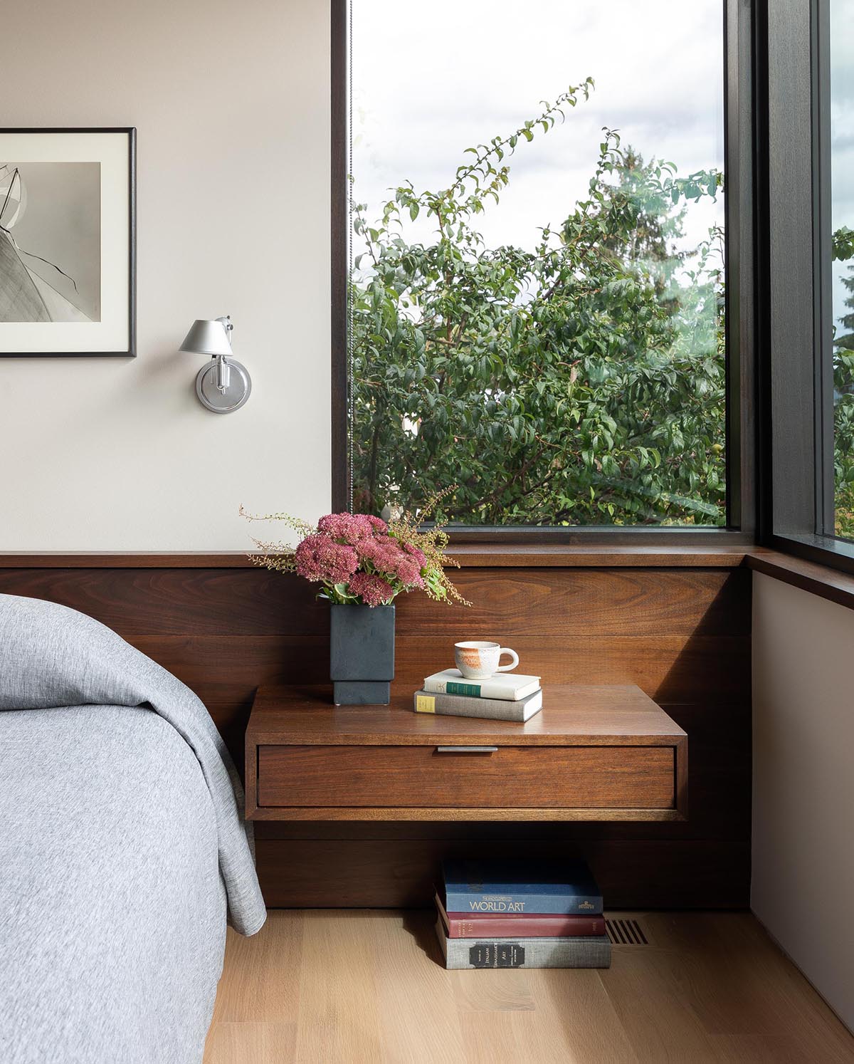 In this modern bedroom, there a wood headboard that provides support for a floating bedside table.