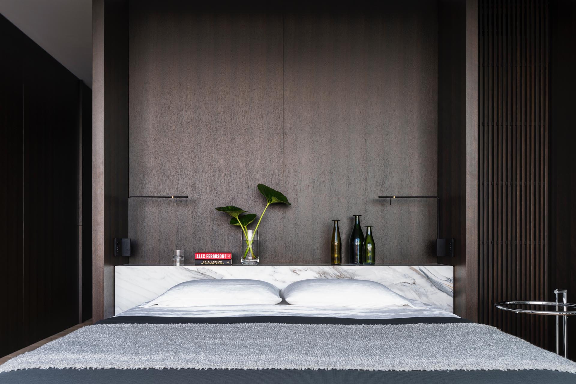 A modern bedroom with marble that acts as a shelf and headboard.