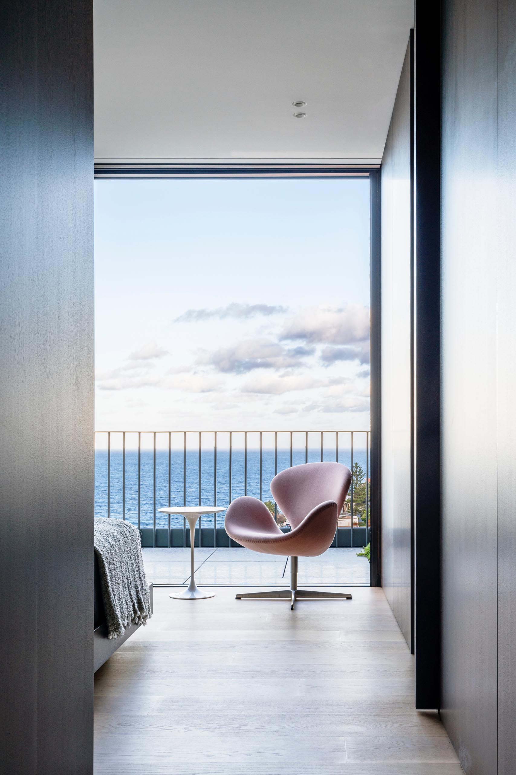 A modern bedroom that opens to a balcony with water views.