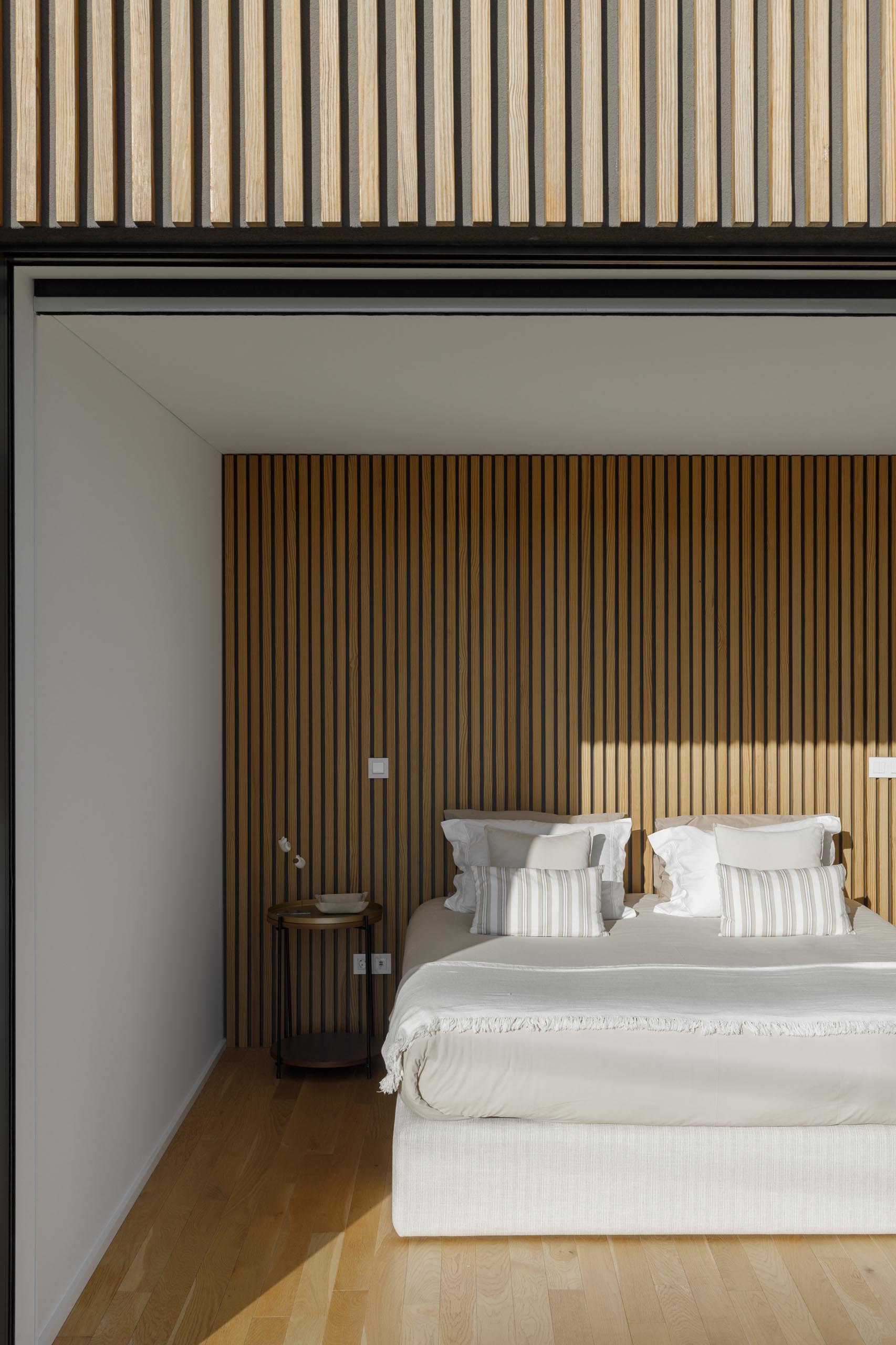 A modern bedroom with a wood slat accent wall.