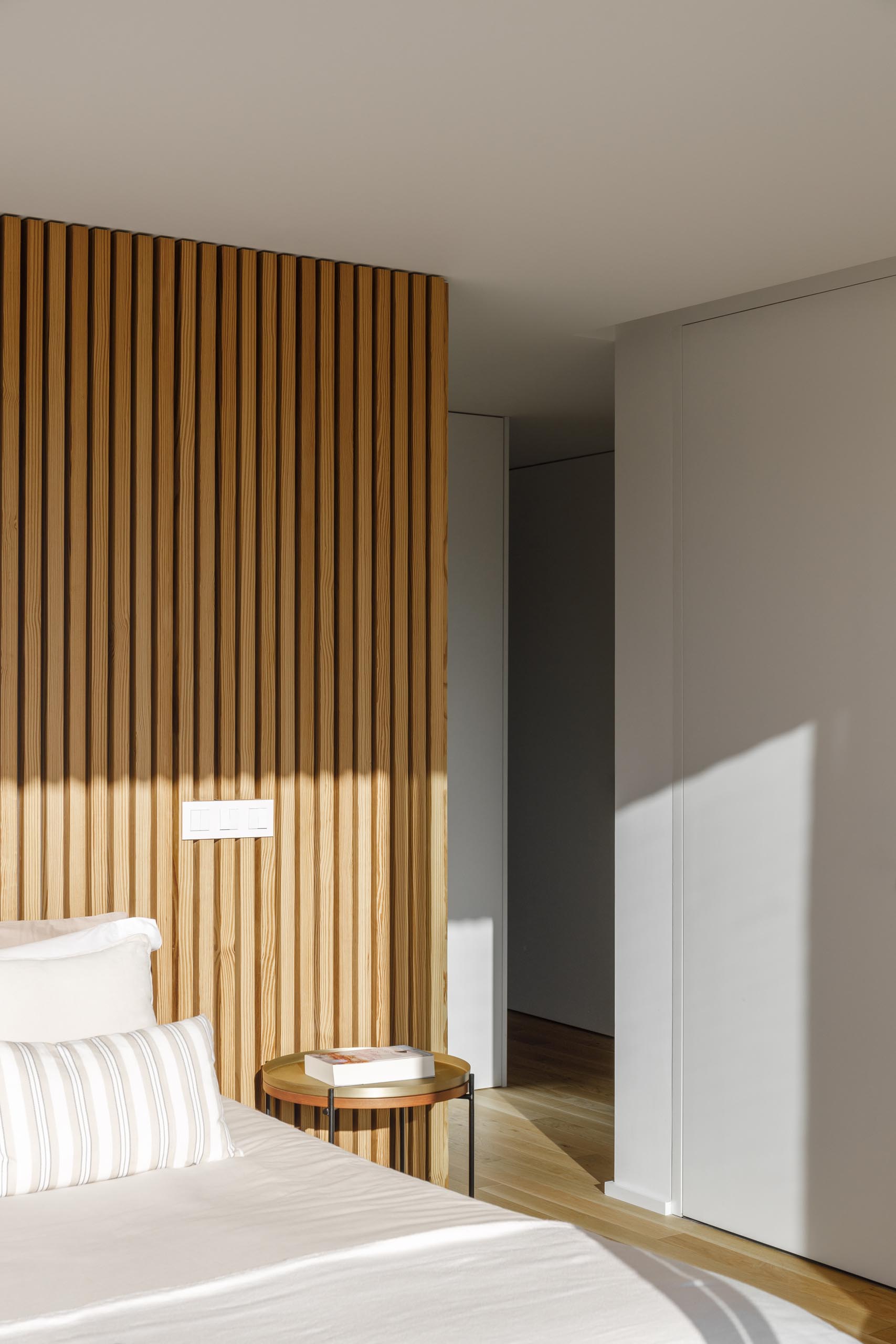 A modern bedroom with a wood slat accent wall.