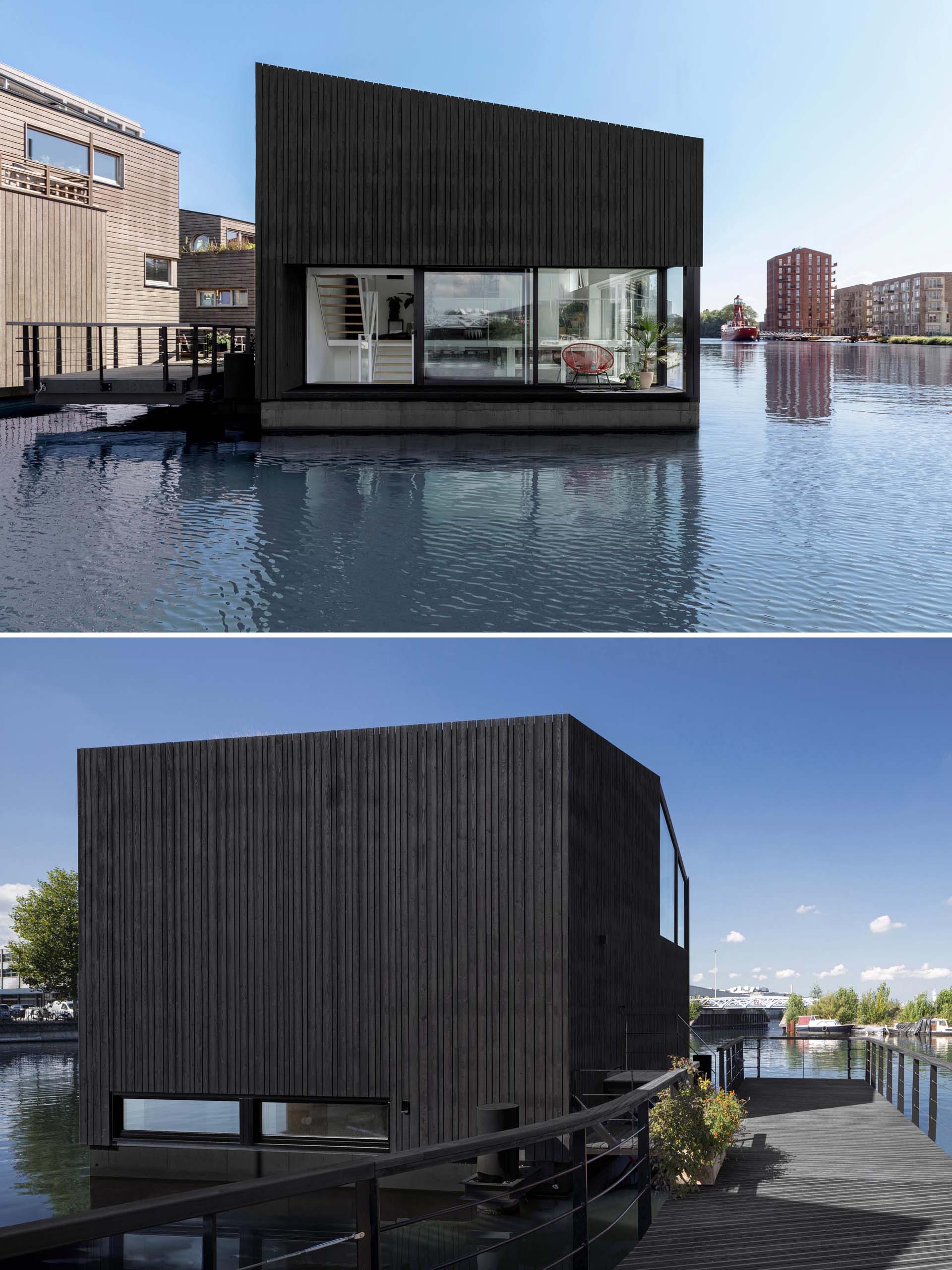 A modern float home with black wood siding and large windows.