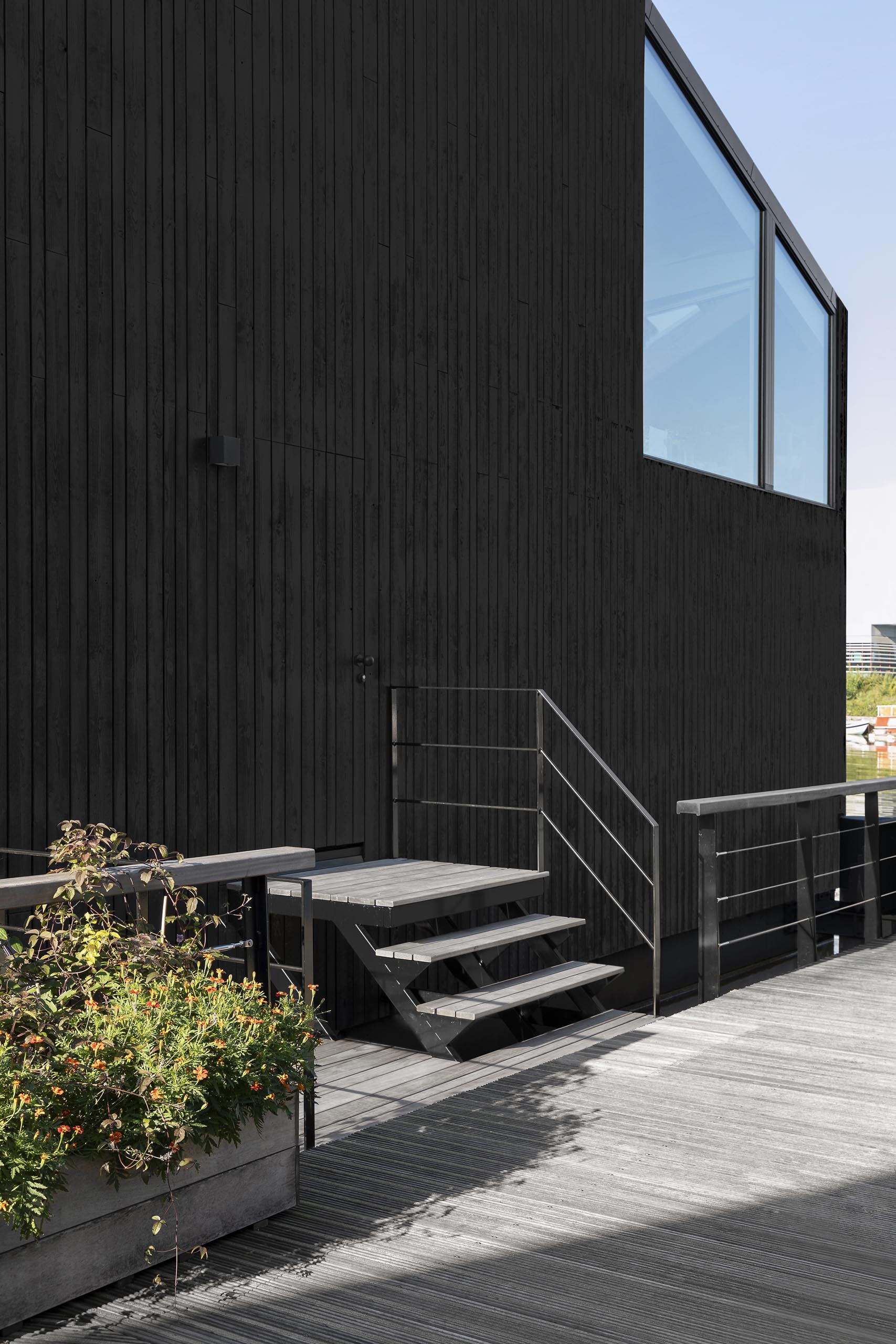 A modern float home with black wood siding.