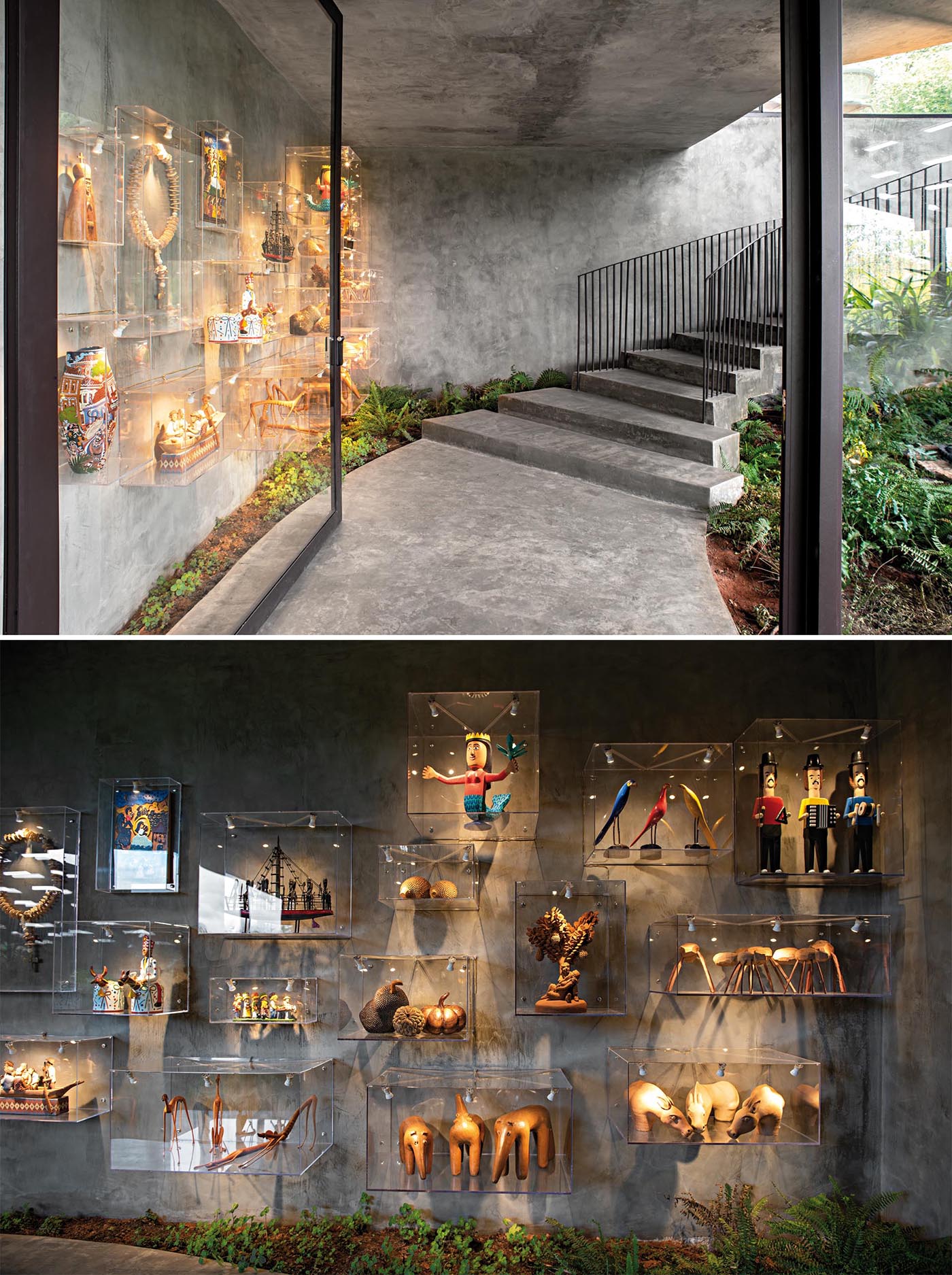 An oversized black-framed glass door, stairs with black railings, wall boxes displaying sculptural items, and gardens, help to create a grand entrance for this modern concrete home.