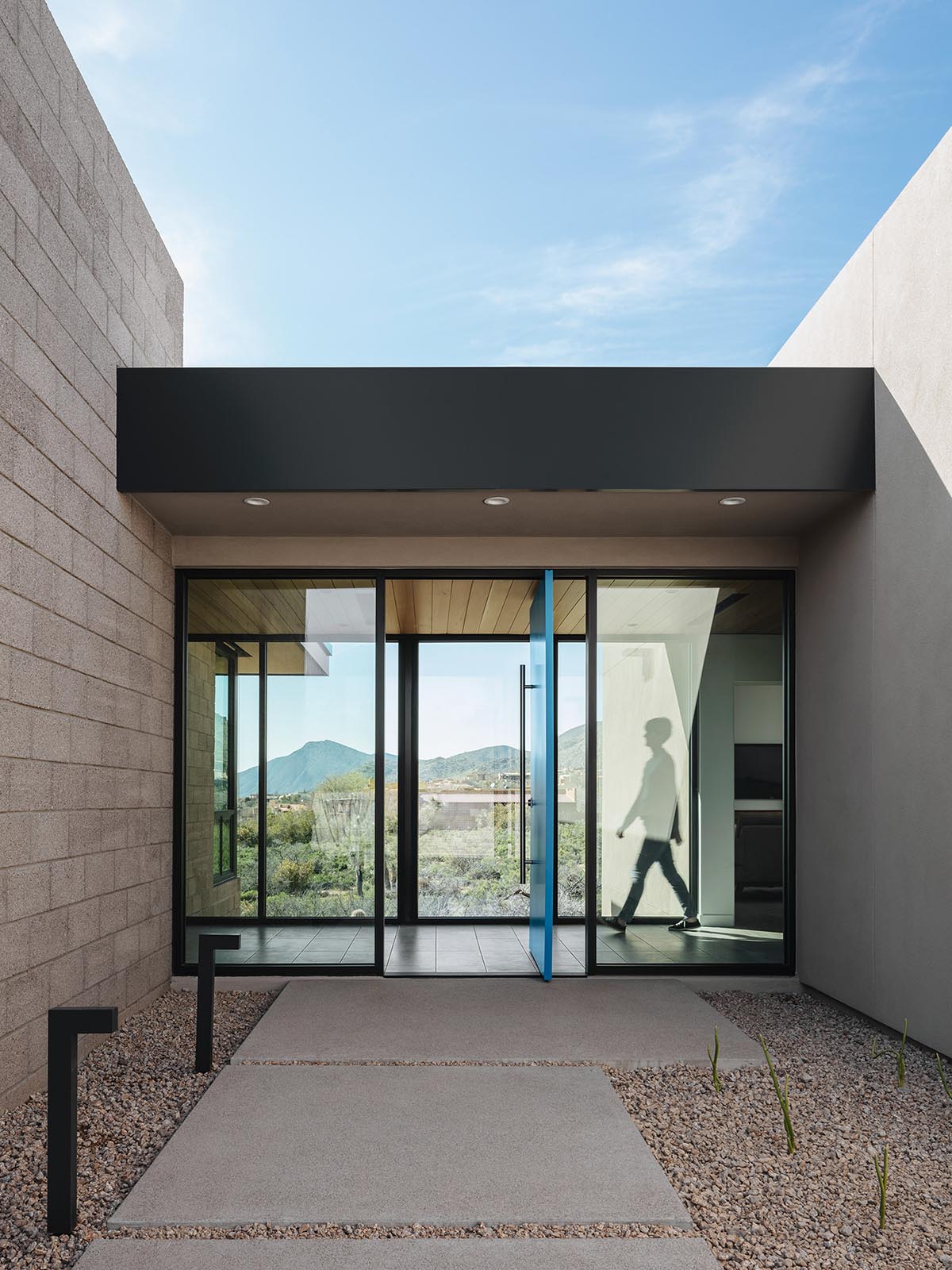 A modern desert home with bright blue pivoting front door.