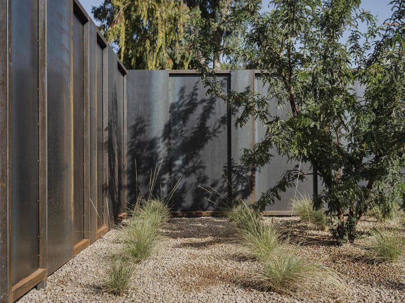 A modern steel fence with minimal landscaping.