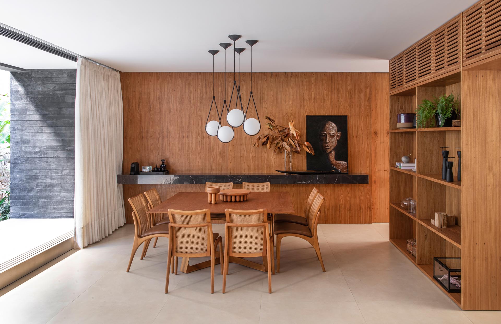 A modern dining room filled with wood and a floating black stone shelf.