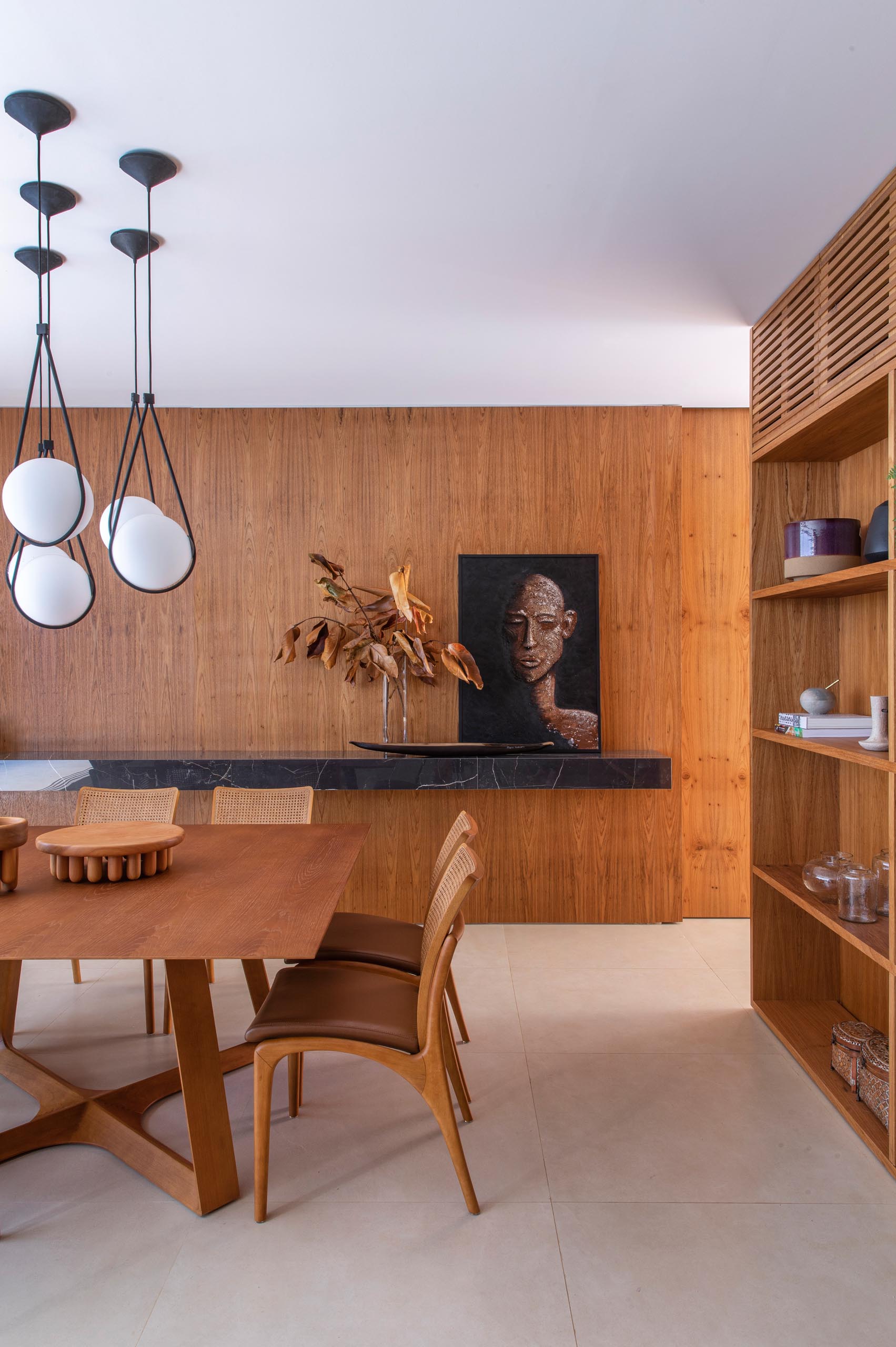 A modern dining room filled with wood and a floating black stone shelf.