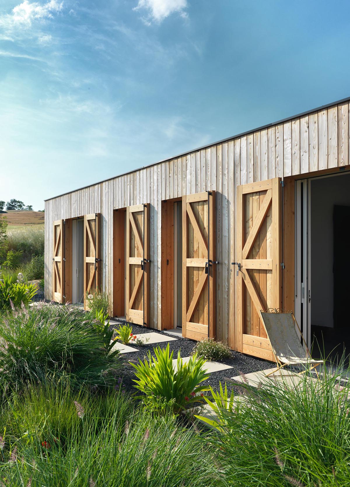 A modern farmhouse with wood shutters to protect the windows and doors.