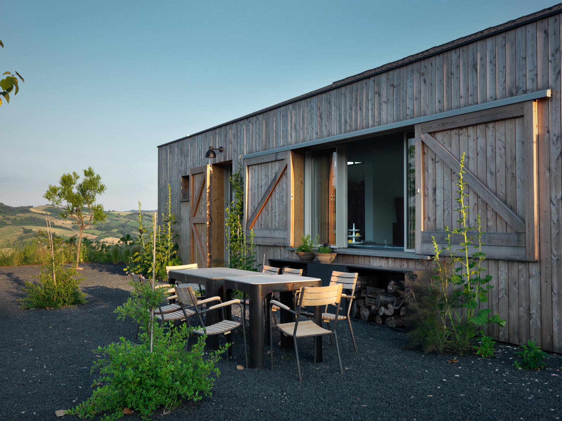 A modern country house with outdoor dining and sliding windows that act as a pass-through to the kitchen.