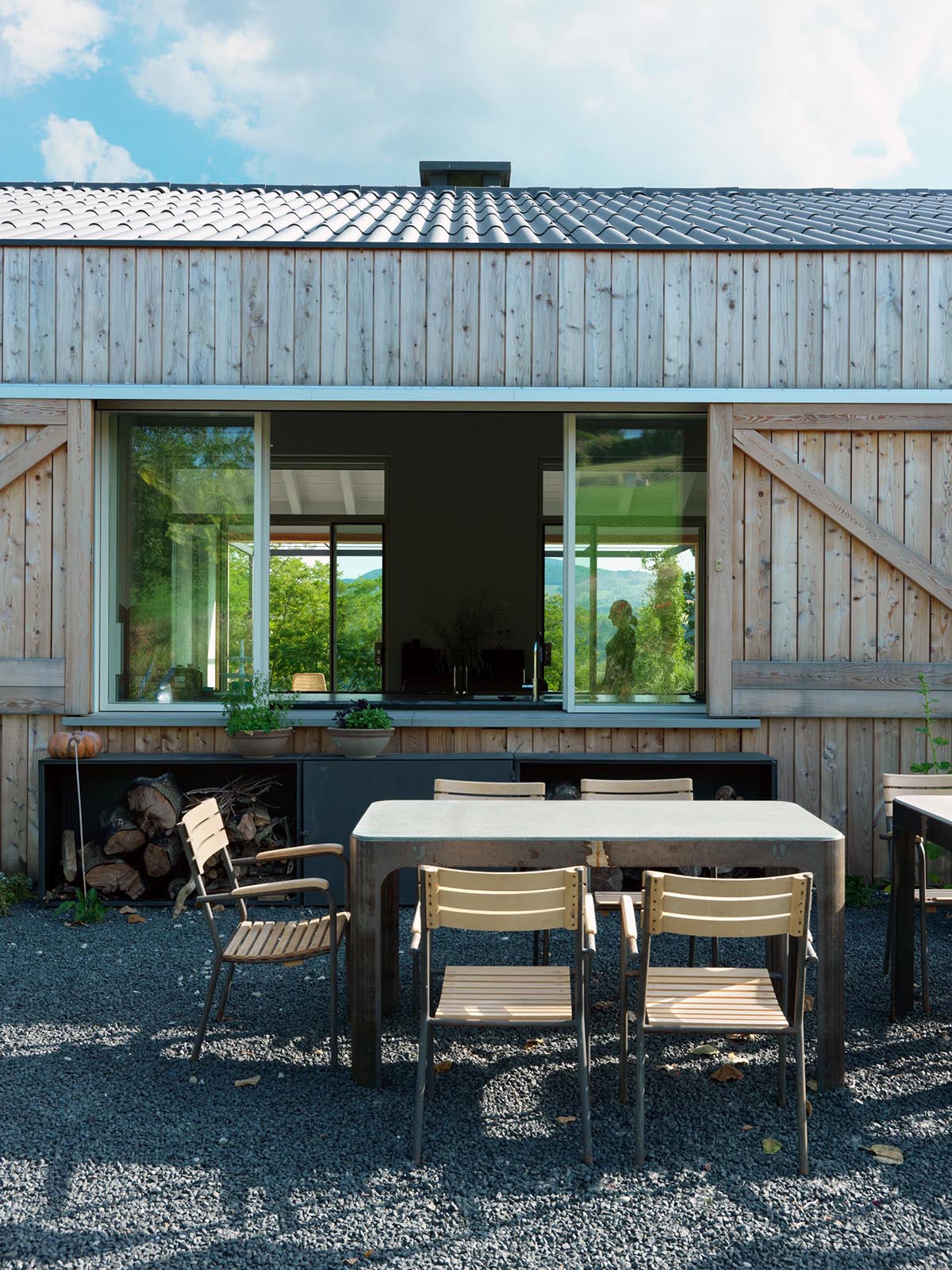 A modern country house with outdoor dining and sliding windows that act as a pass-through to the kitchen.