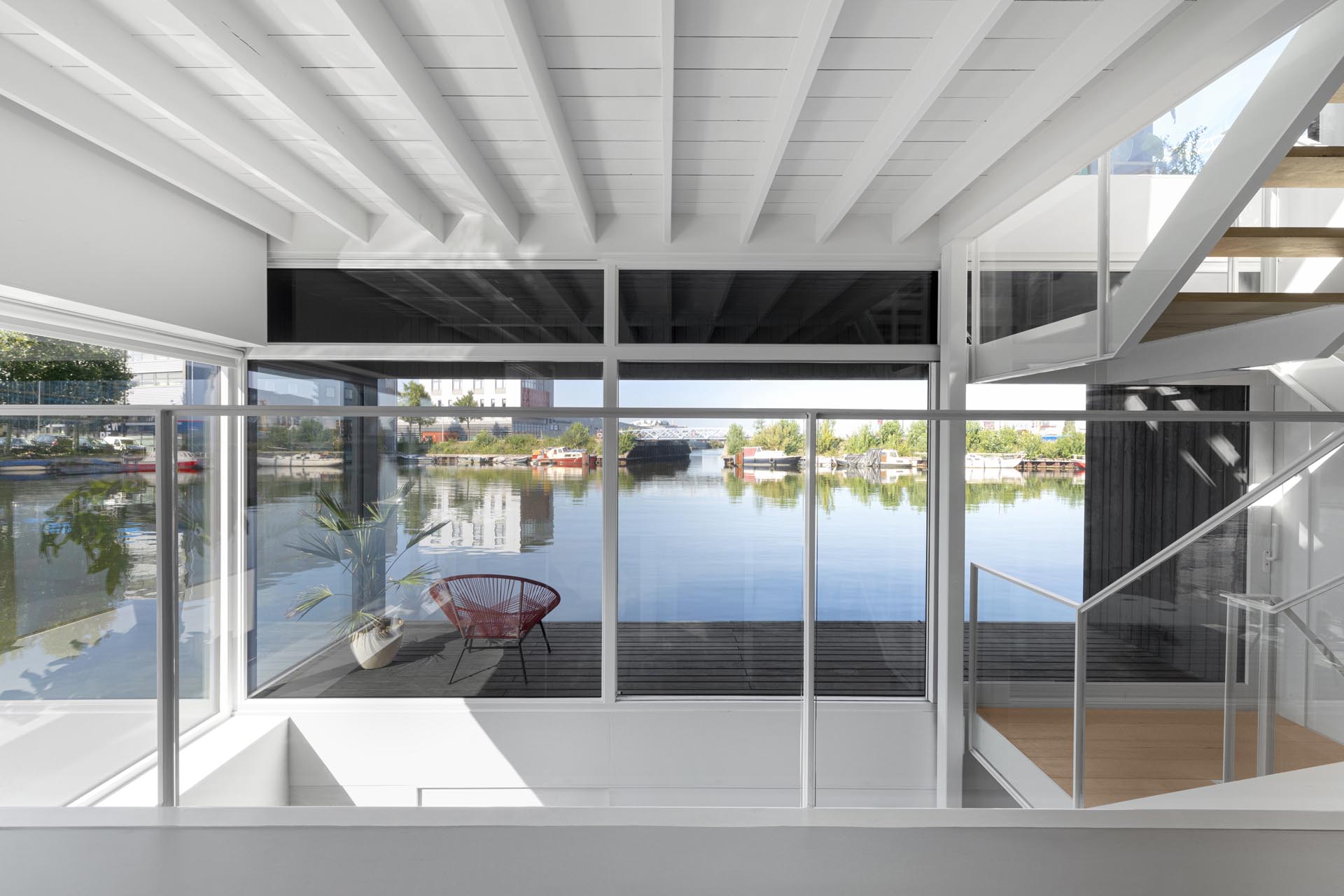 A white staircase in this modern float home matches the walls and ceiling, connects the various levels of the float home, and adds a warm wood element to the space.