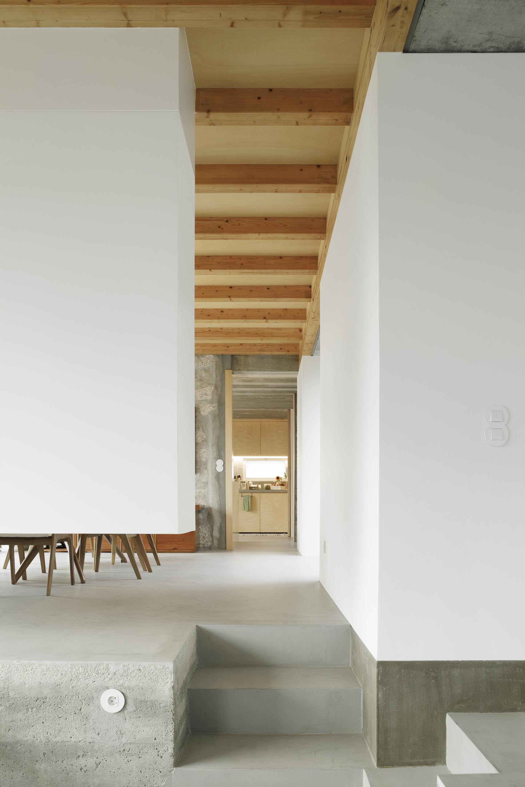 Một ngôi nhà hiện đại với sàn bê tông, tường trắng và trần gỗ.