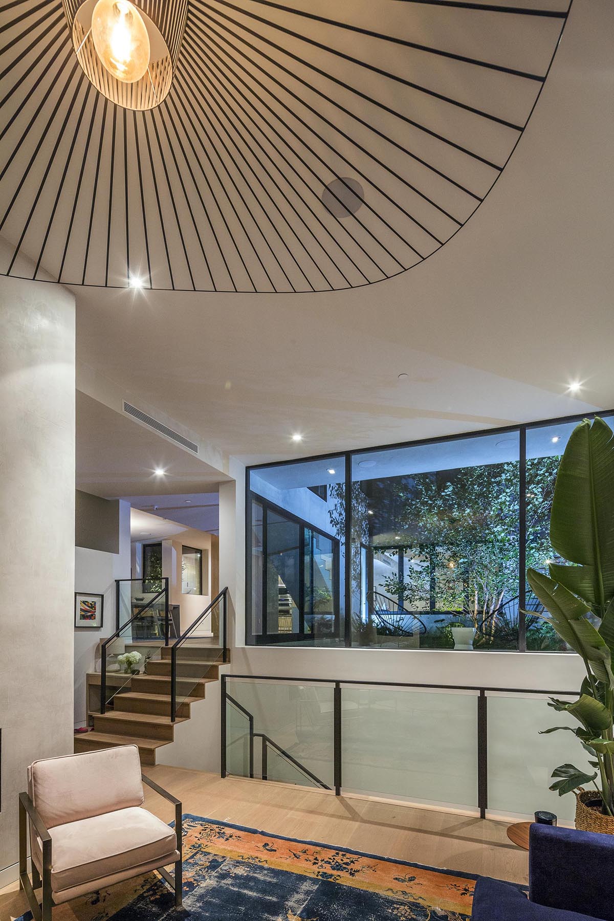 Stairs connect to the social areas of the house, while large windows provide views of a courtyard.