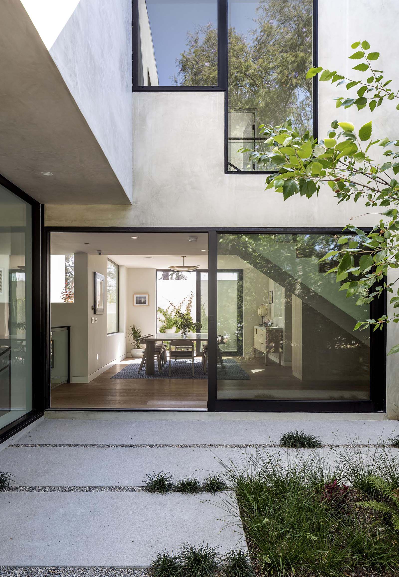 An oversized black framed sliding glass door opens the dining room to a courtyard.