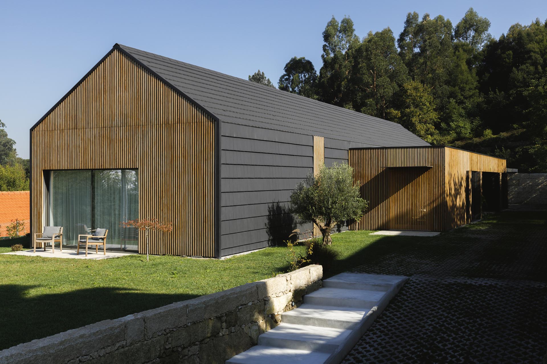 A modern black house with wood accents.