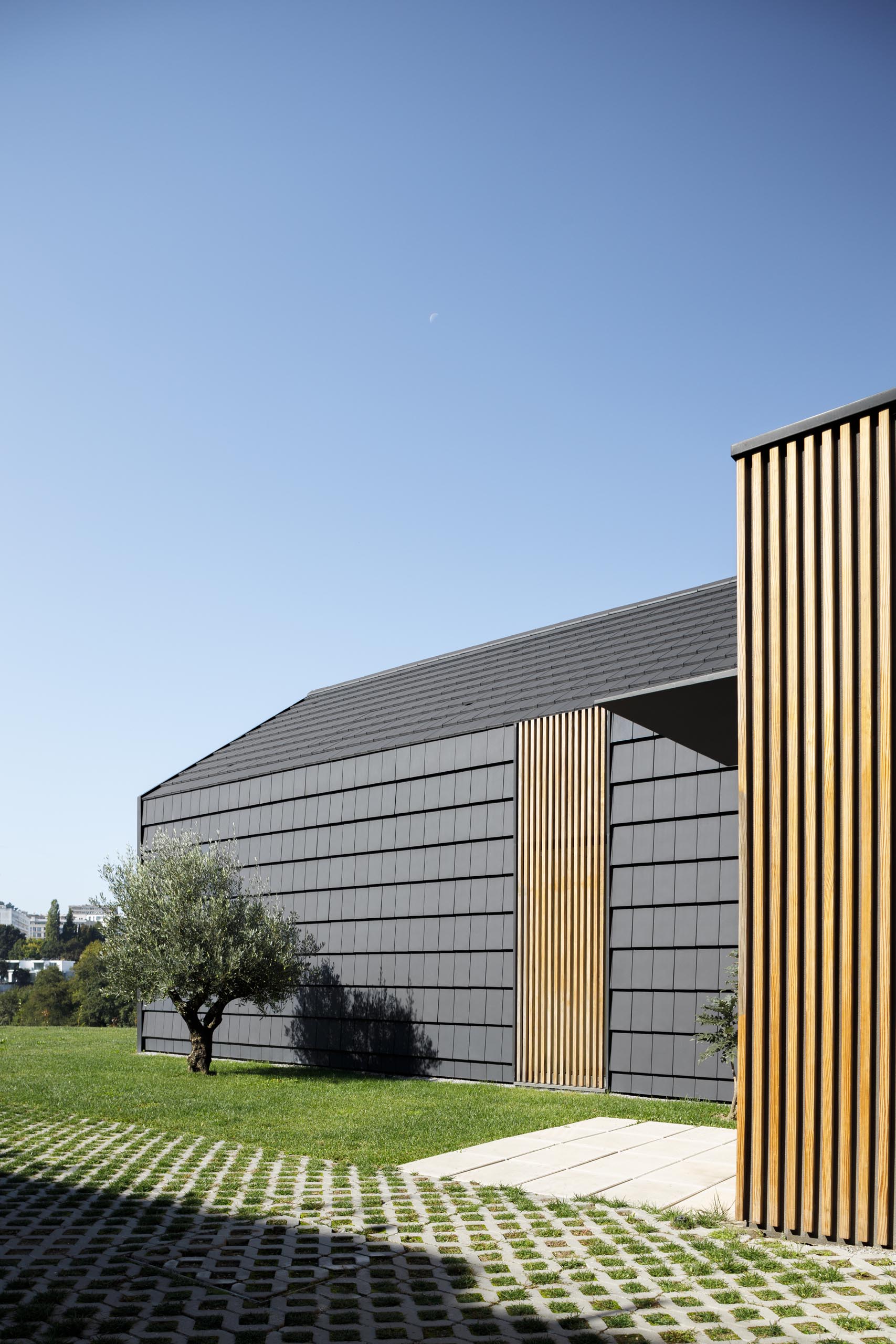 A modern home with black shingle exterior and wood slat accents.